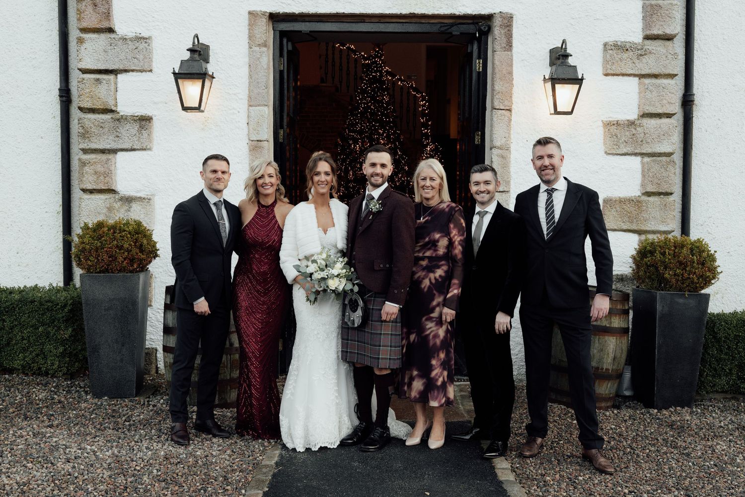 Group photo of wedding party members standing together outside a historic stone building.