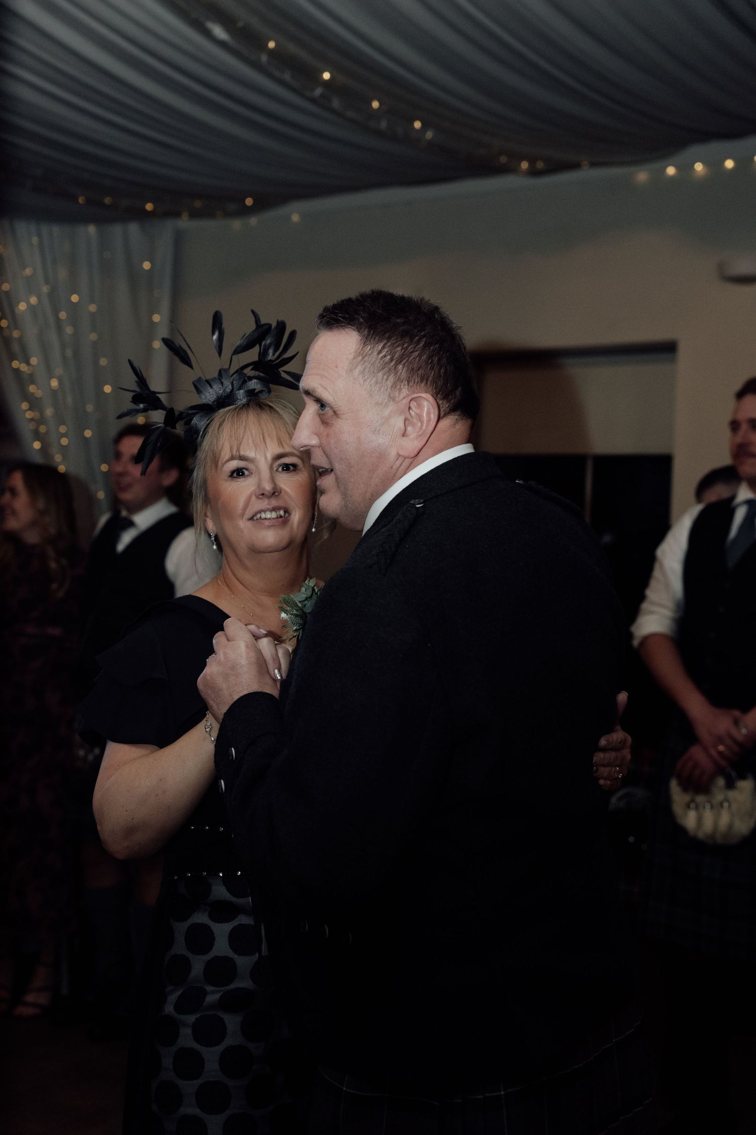 Wedding guests dancing and laughing together at an evening reception.