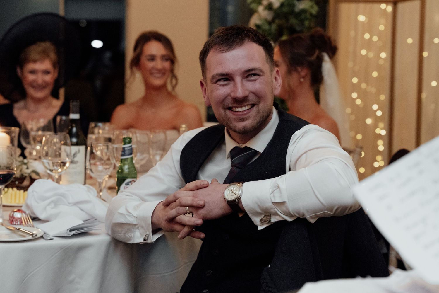 Wedding reception attendees share laughter and conversation at decorated banquet tables.
