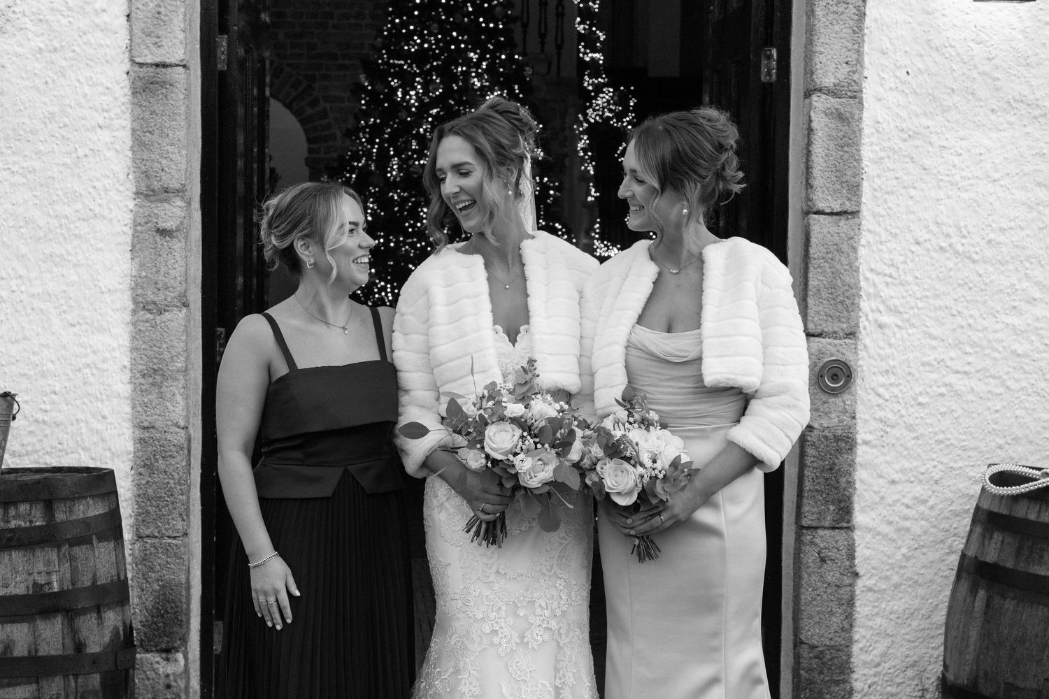 Wedding party members gathered near stone entrance with festive lighting and floral arrangements.