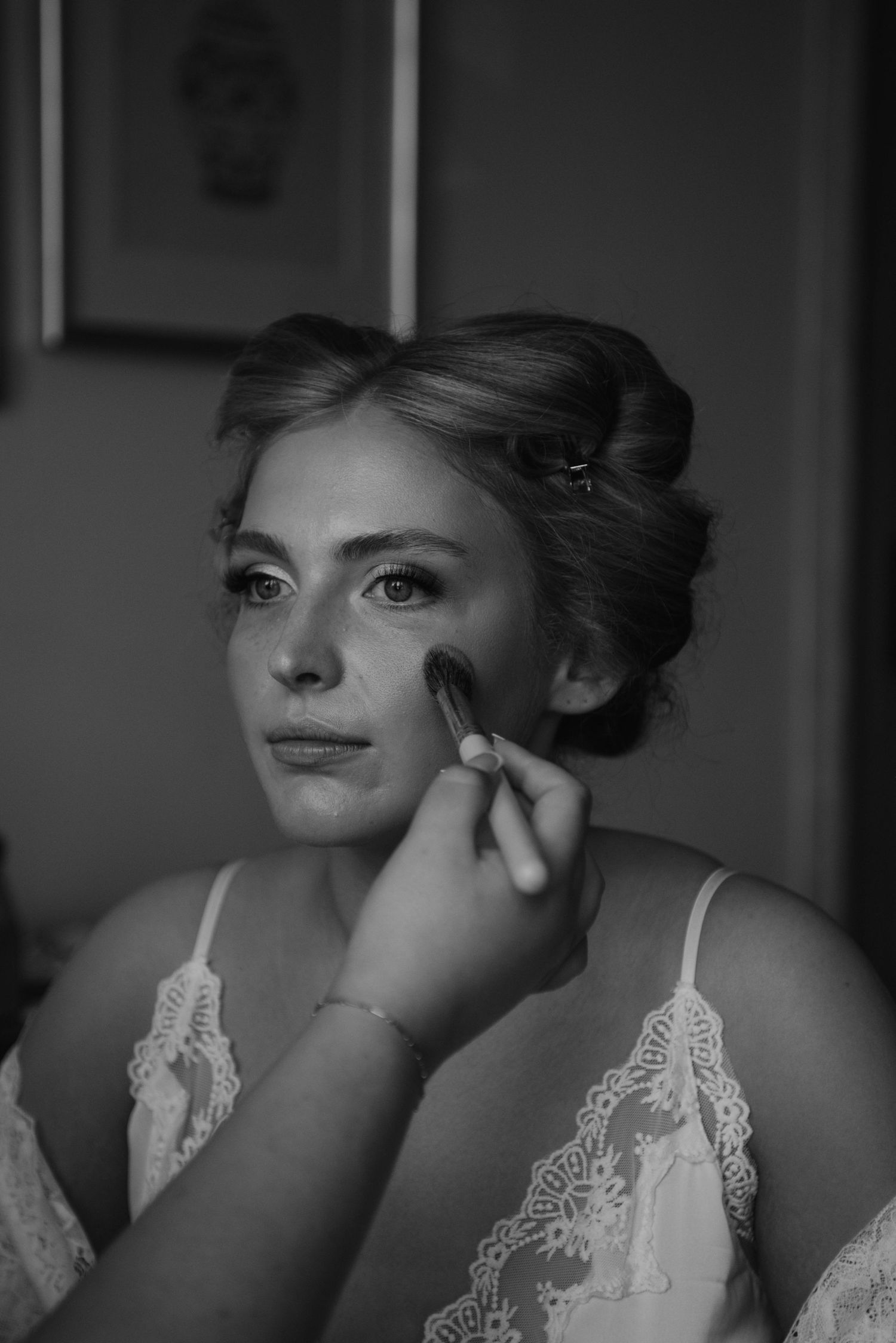 Black and white photos showing makeup application with delicate lace details in bridal preparation sequence.