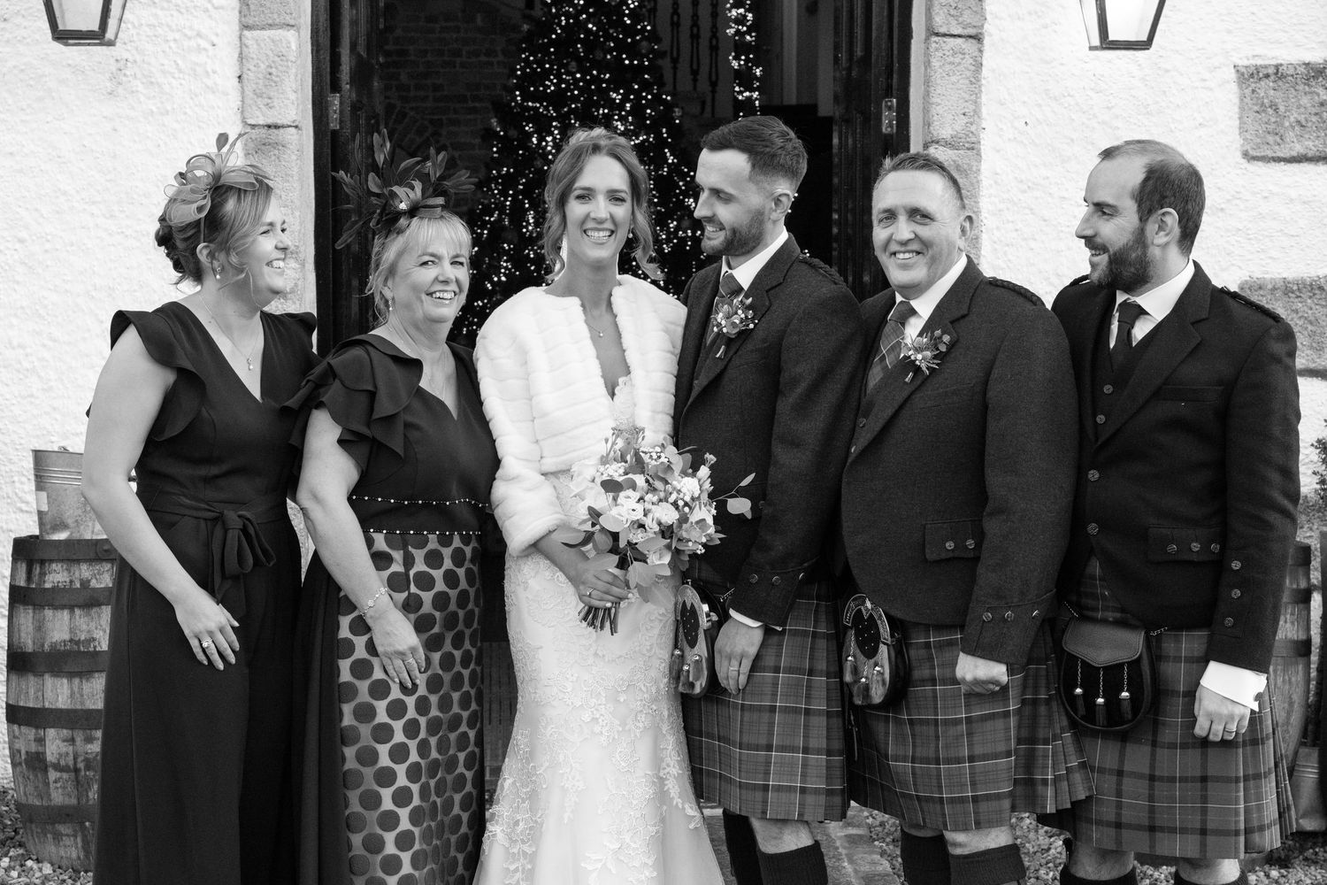 Monochrome image of wedding group lined up outside building entrance.