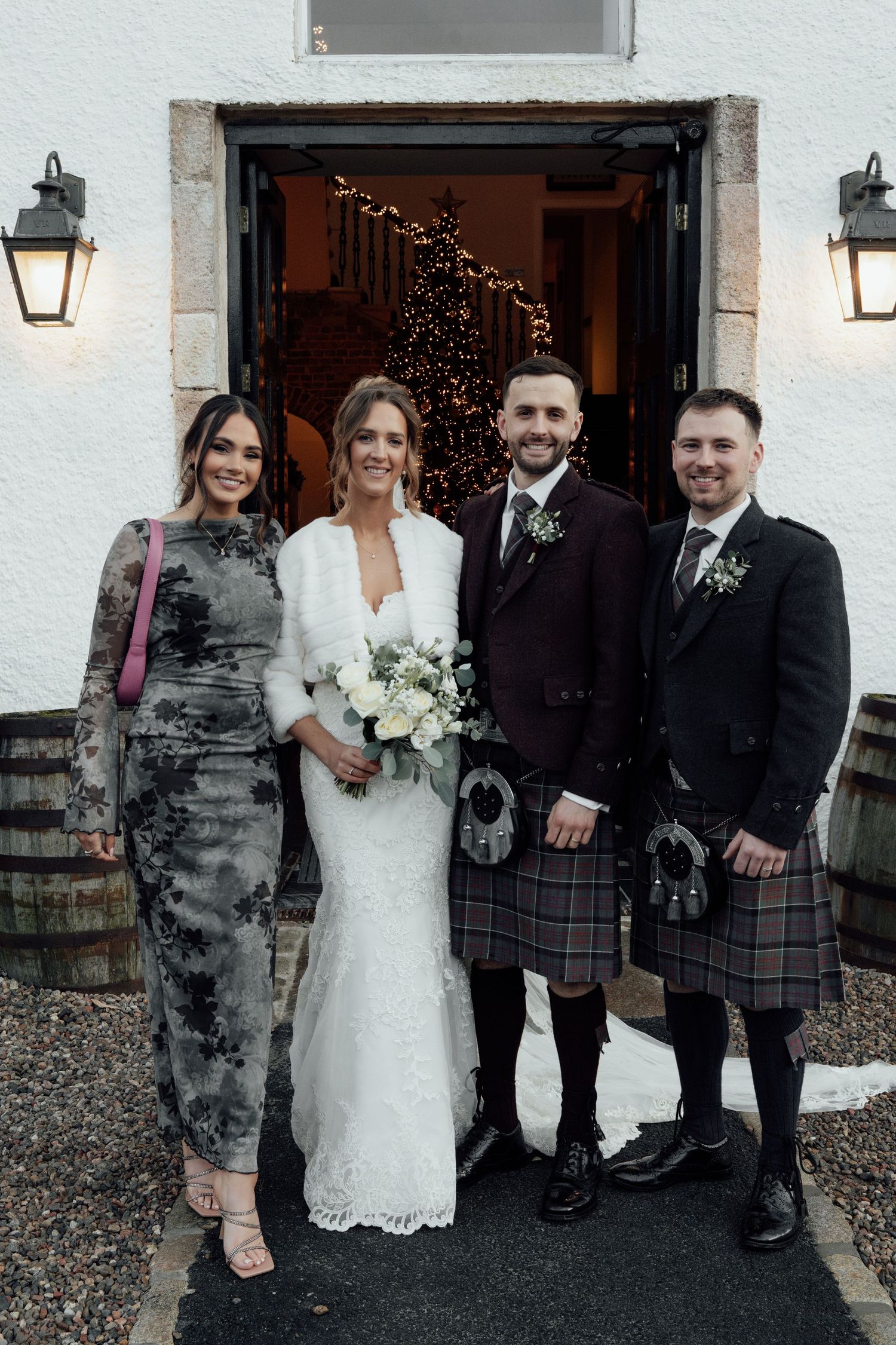 Wedding party members in kilts and formal attire gather for group photos outside.