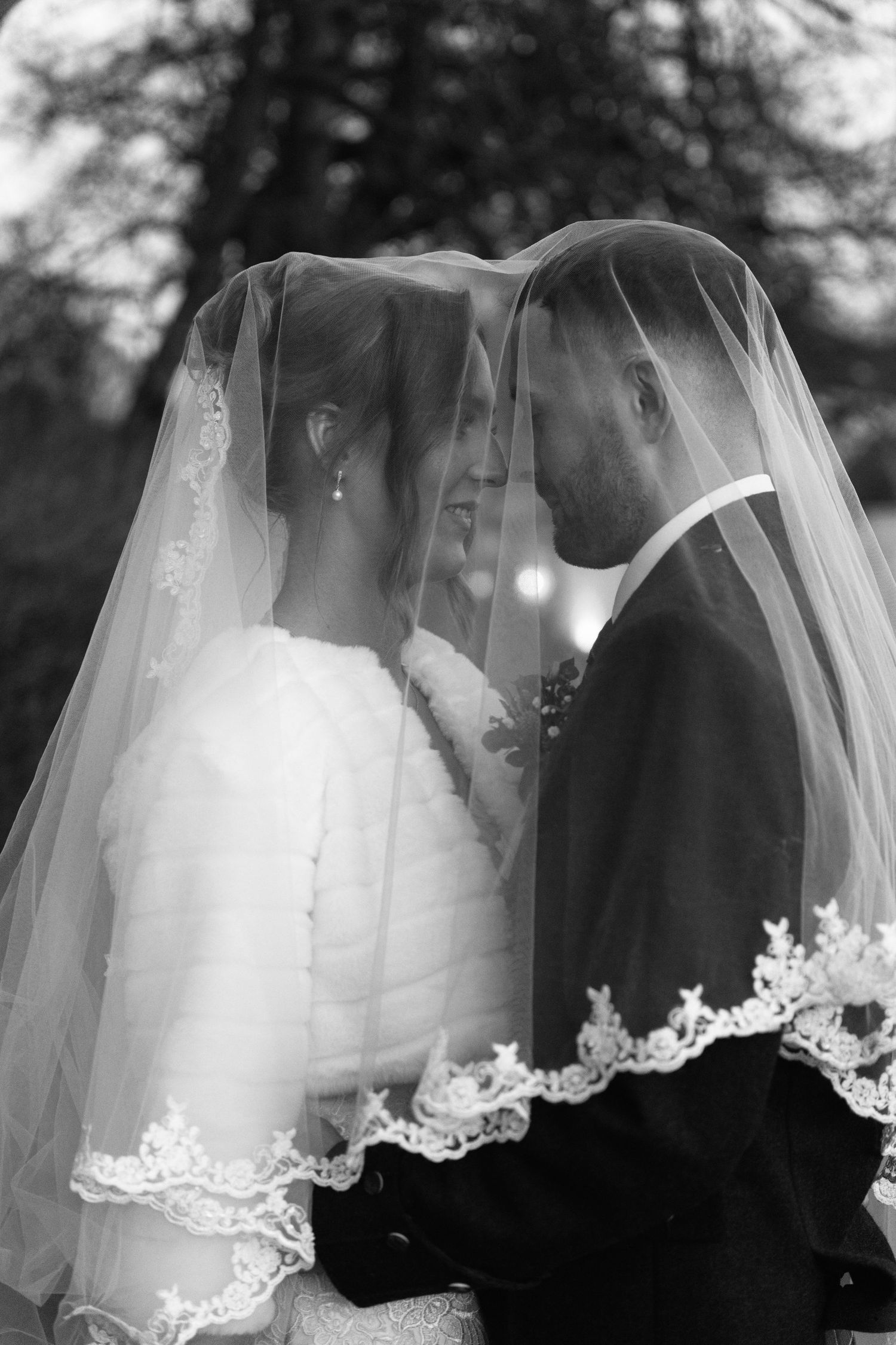Artistic wedding photos featuring close-ups of the couple beneath a detailed lace veil.