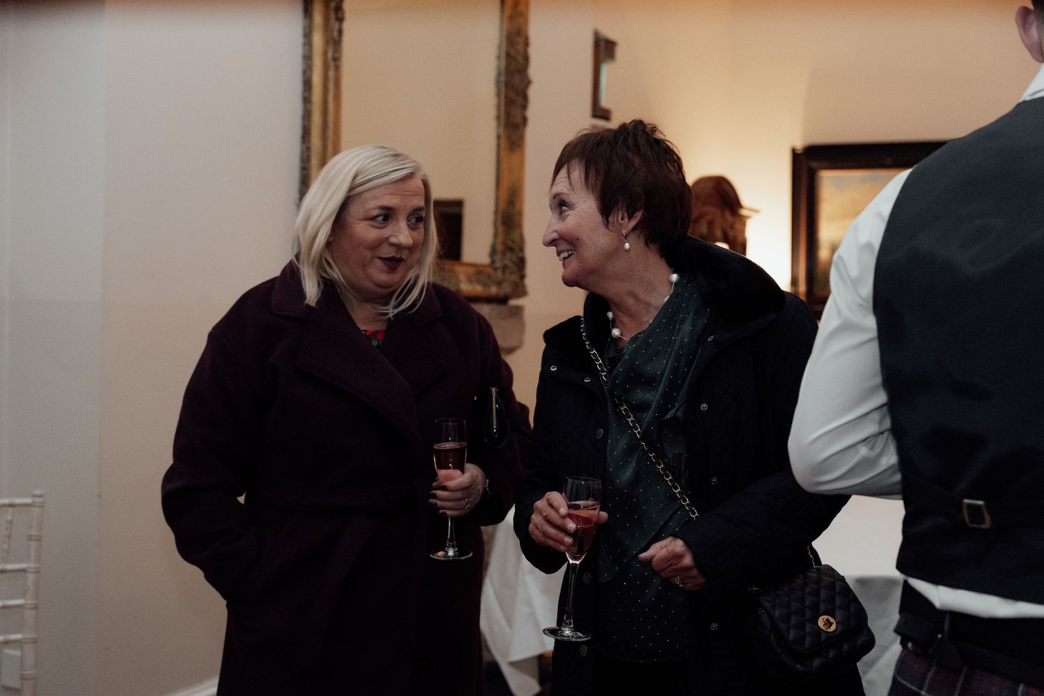 Wedding guests chatting and enjoying drinks at an indoor celebration.