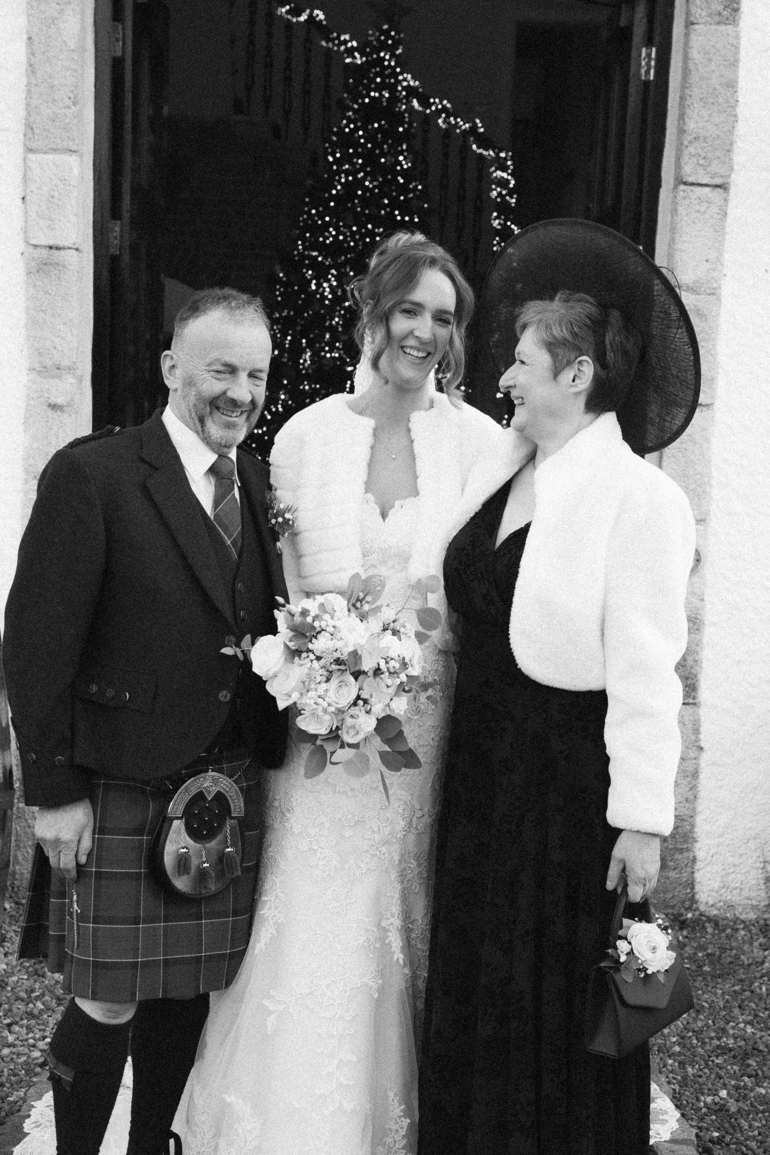 Wedding party laughing together outside venue with Scottish formal wear.