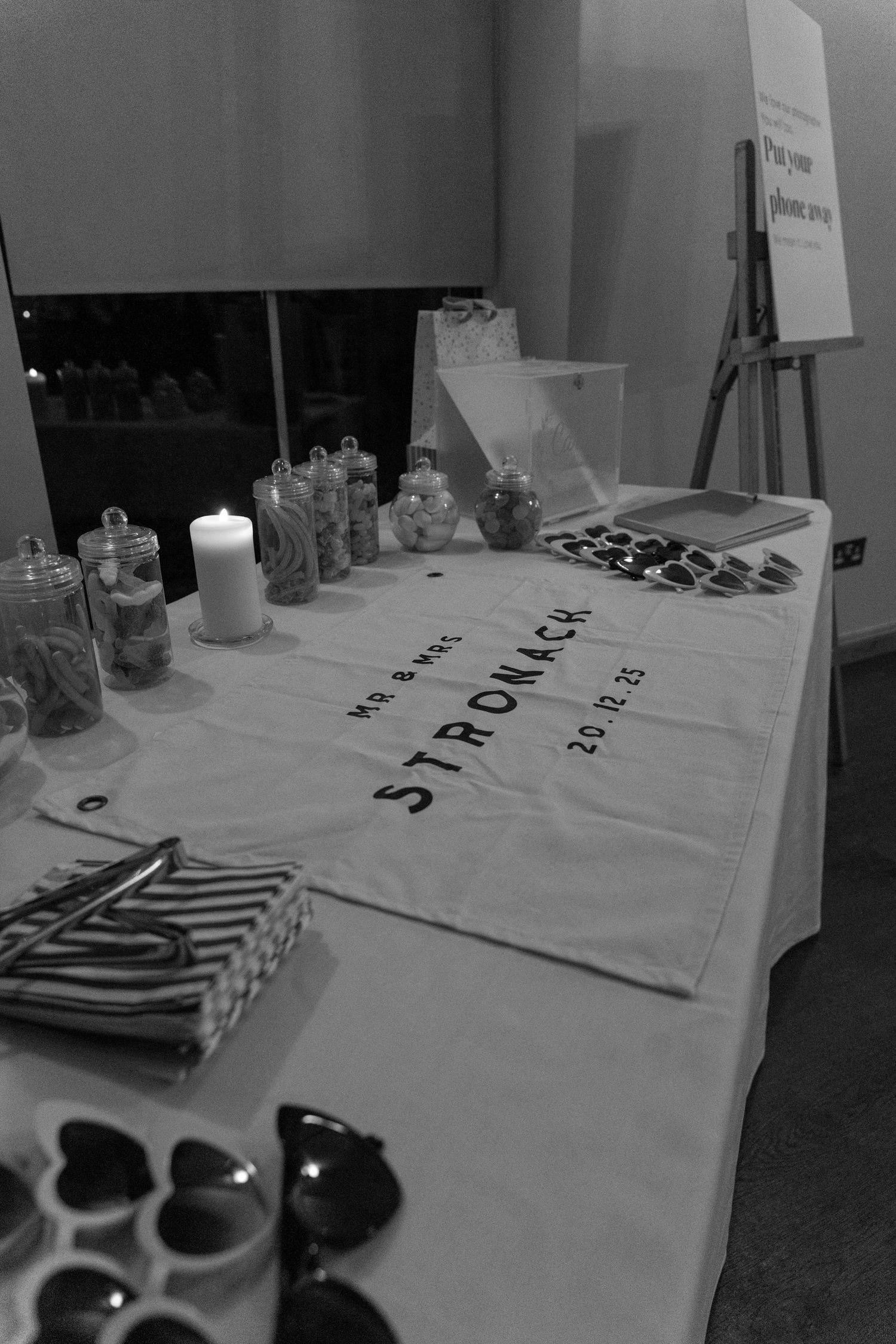 Black and white photo of wedding reception table setup with candles and decorative items.
