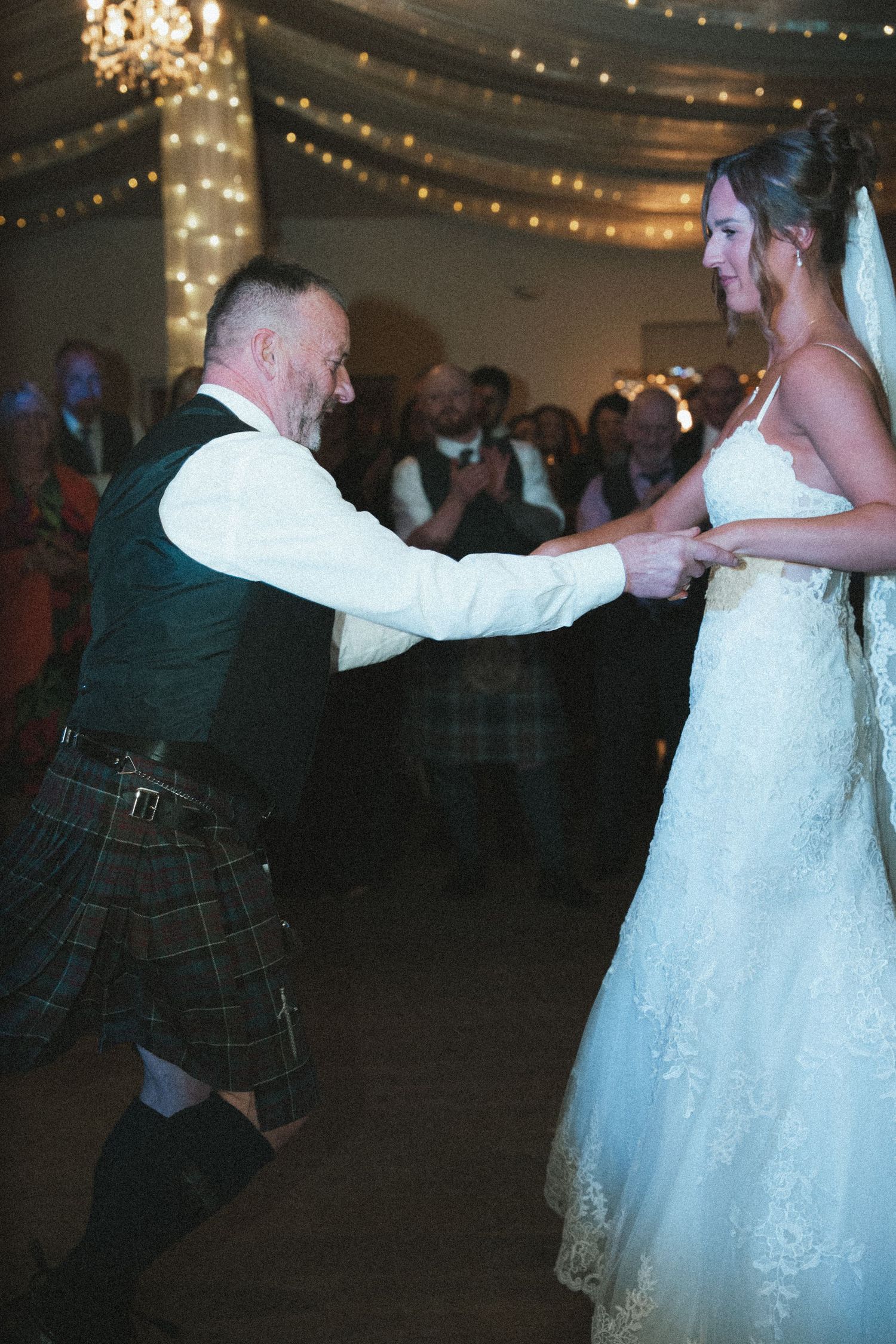 A couple shares a romantic dance moment at their wedding reception with elegant draped decor.