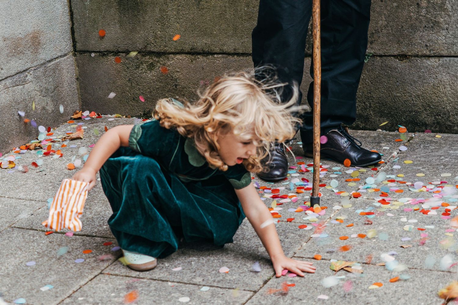 People kneel on concrete ground scattered with colorful confetti in an artistic scene.