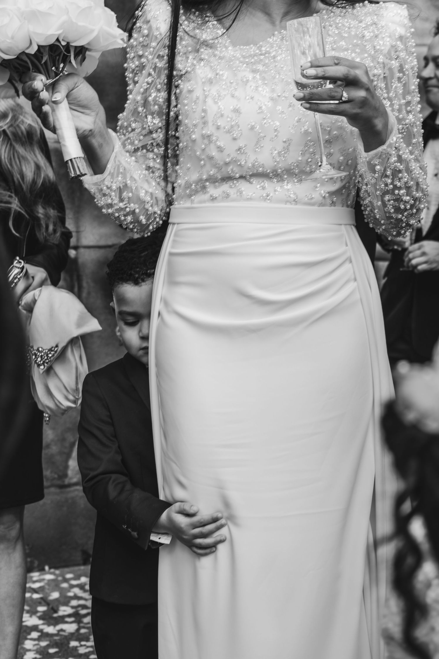 Black and white photo series showing close-up details of a bride's white lace wedding dress and bouquet.