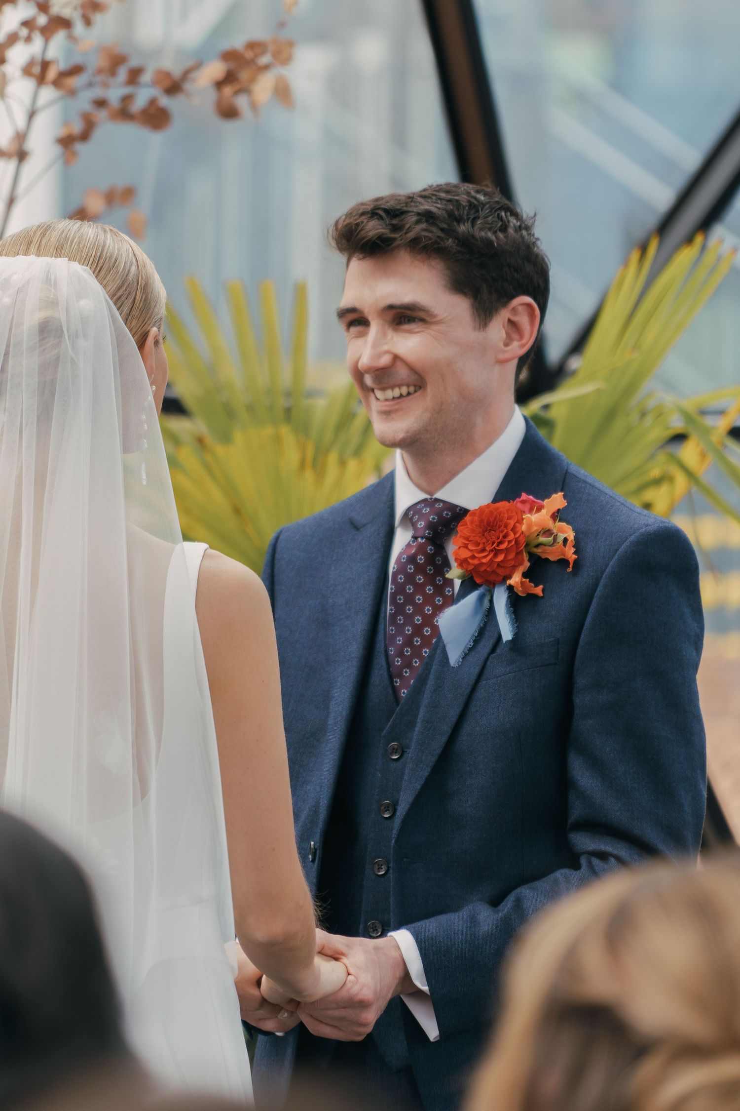 A joyful wedding ceremony moment showing a couple exchanging vows with bright orange floral accents.