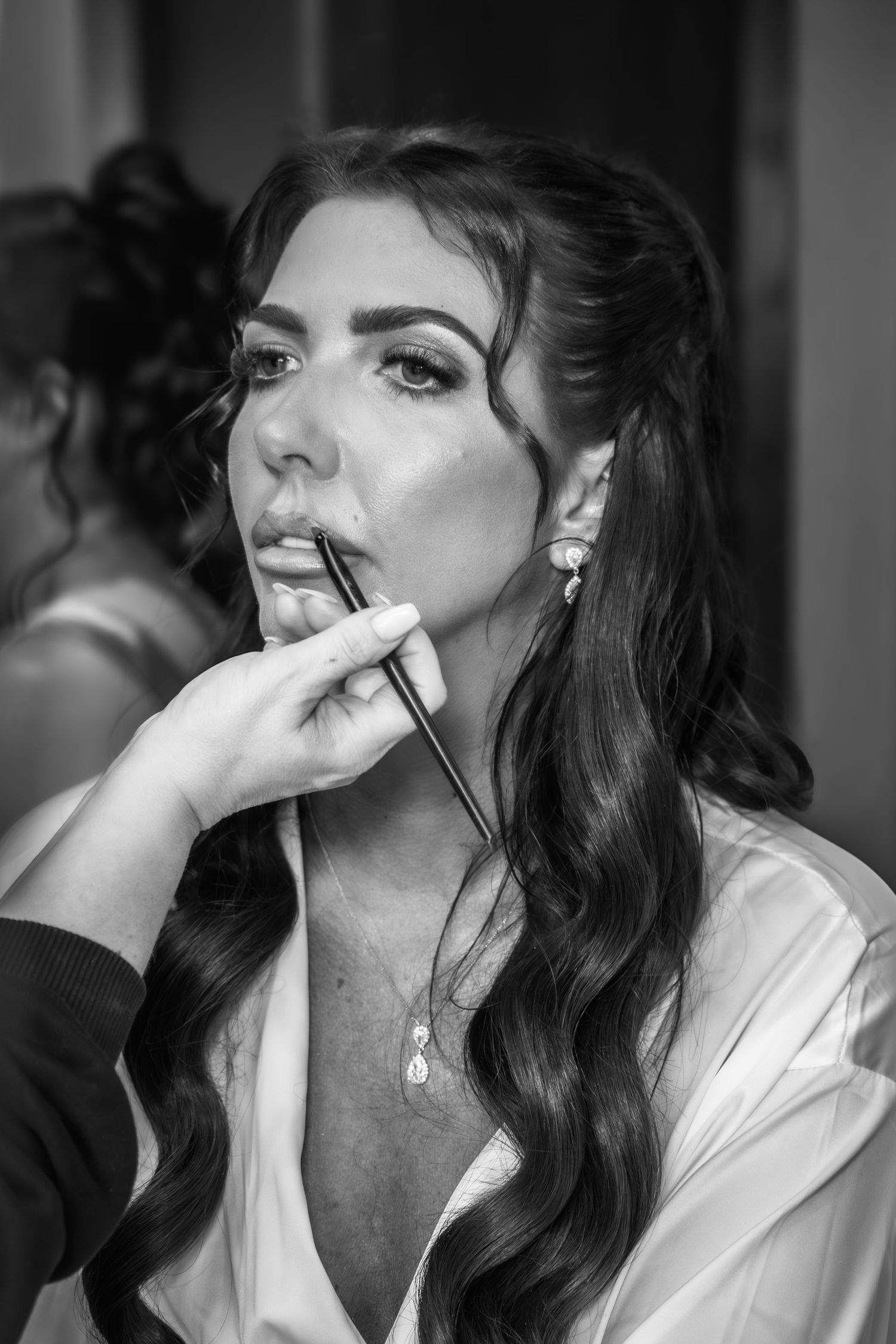 Black and white photo series showing a person getting makeup applied while wearing a white robe.