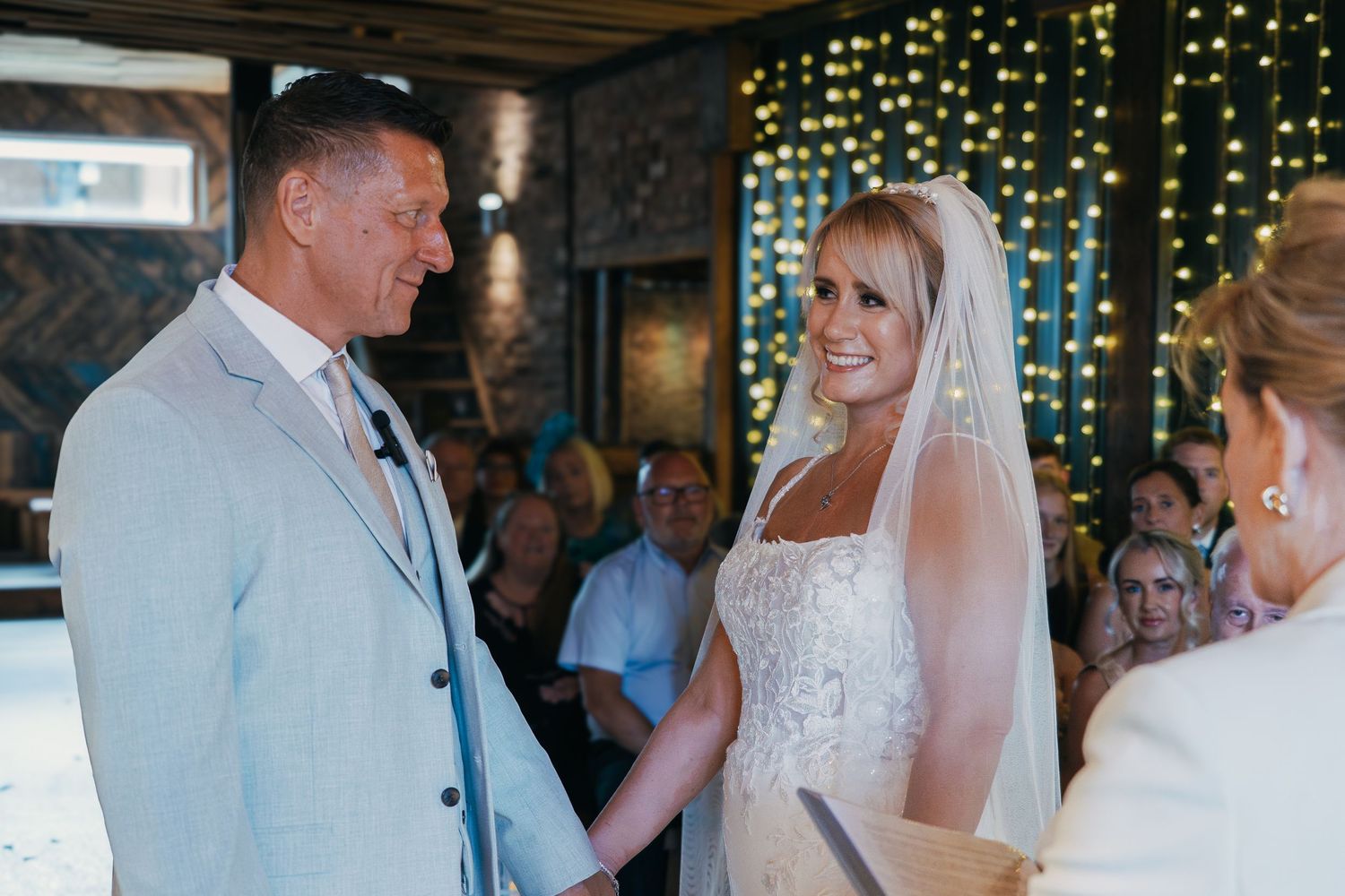 A wedding celebration scene with string lights and exposed brick walls in the background.