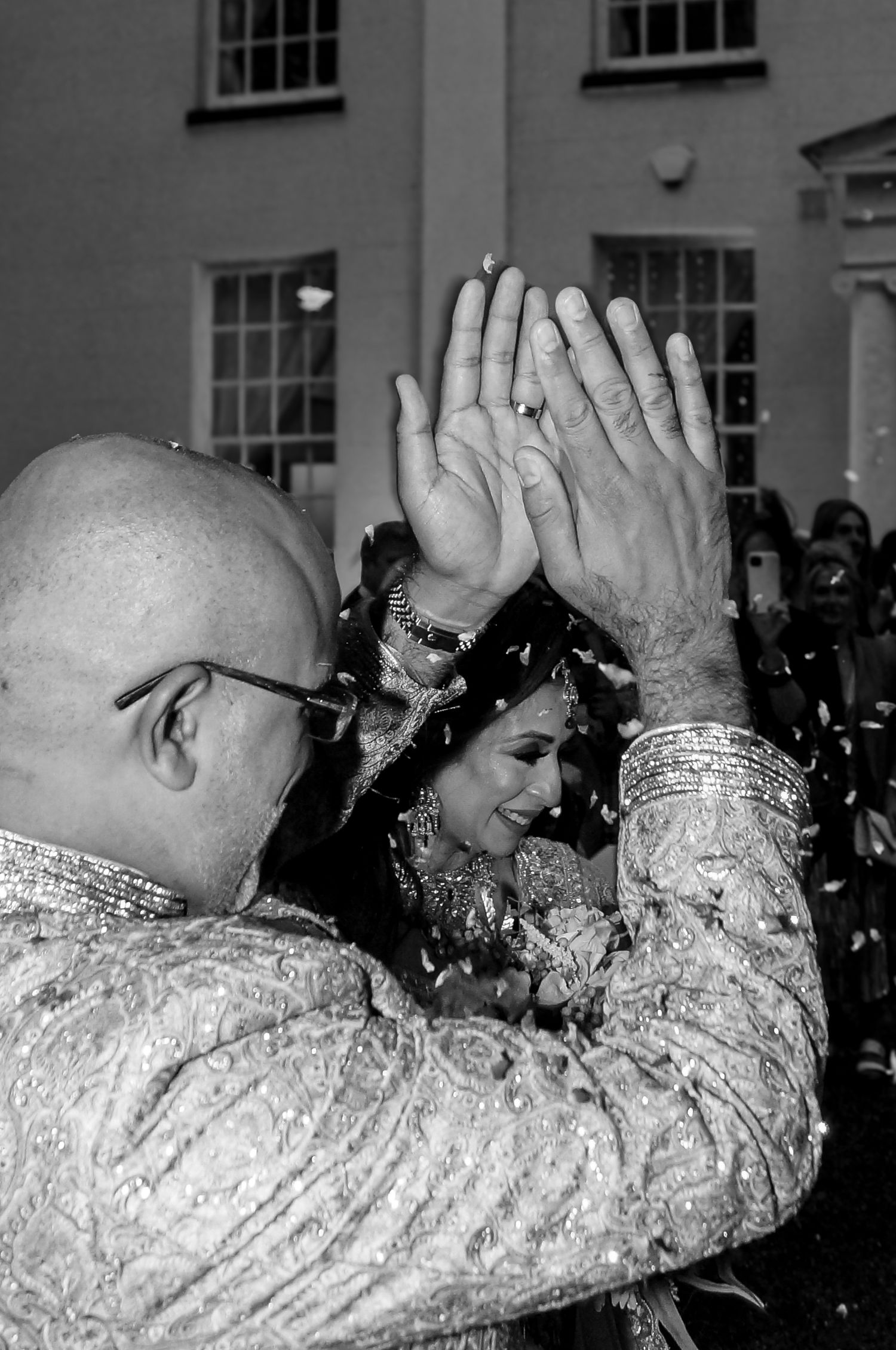 People raising hands in unison wearing patterned clothing at indoor gathering.