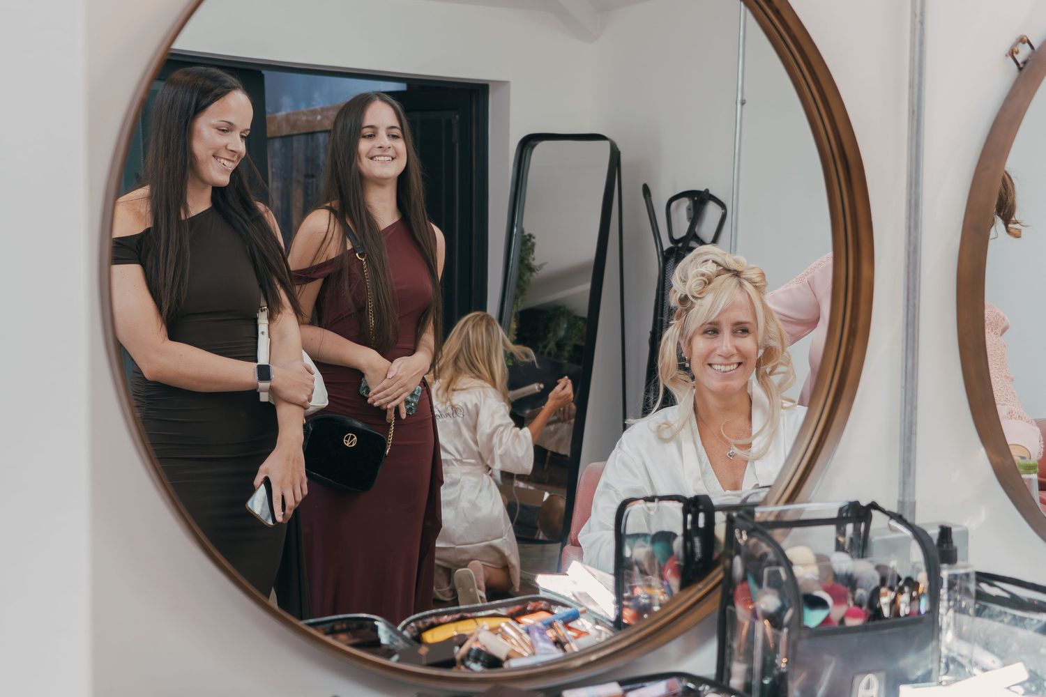 Three framed circular mirrors on wall reflect group of people at a social gathering.