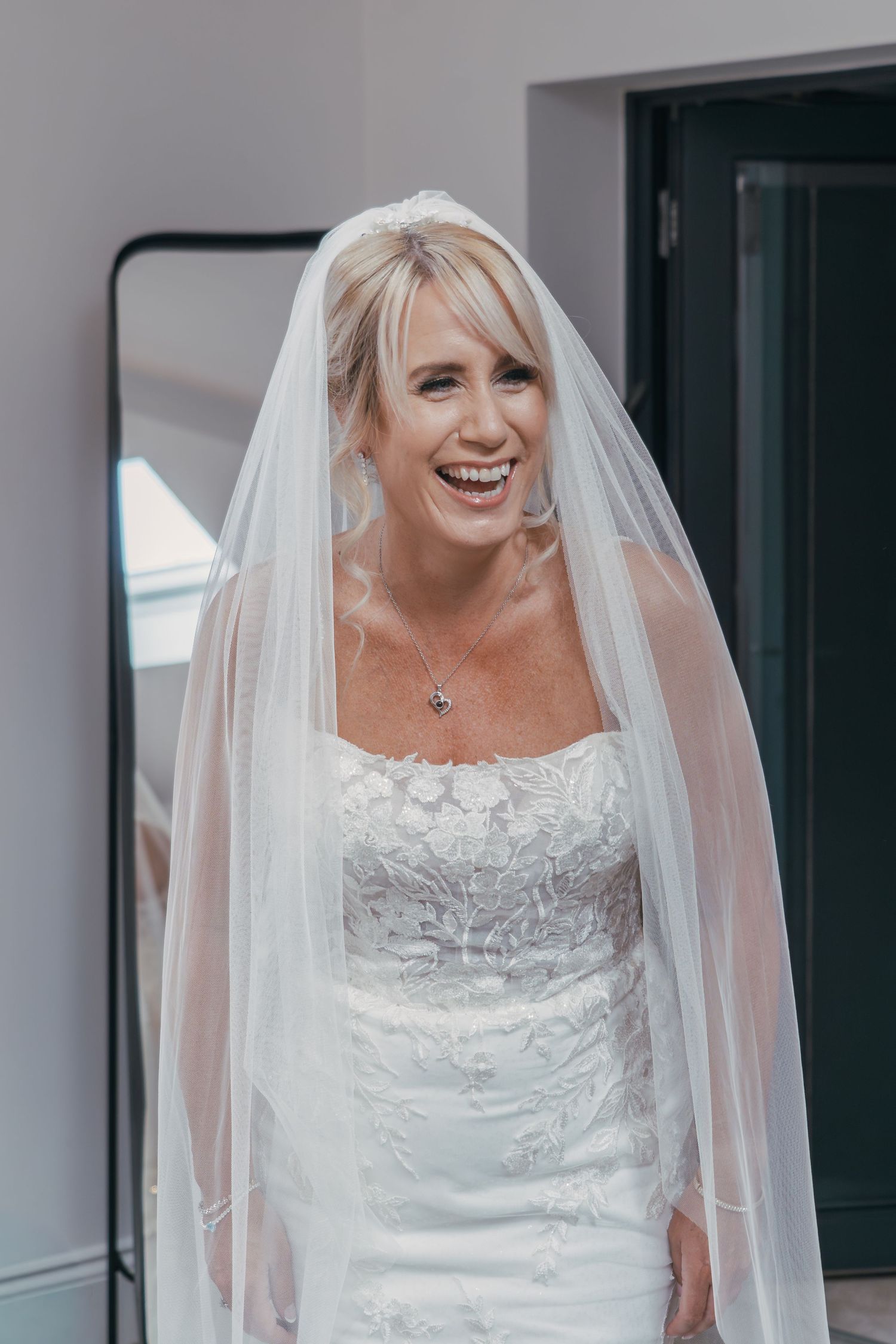 A bride in a white lace wedding dress and flowing veil smiles joyfully in a series of candid moments.
