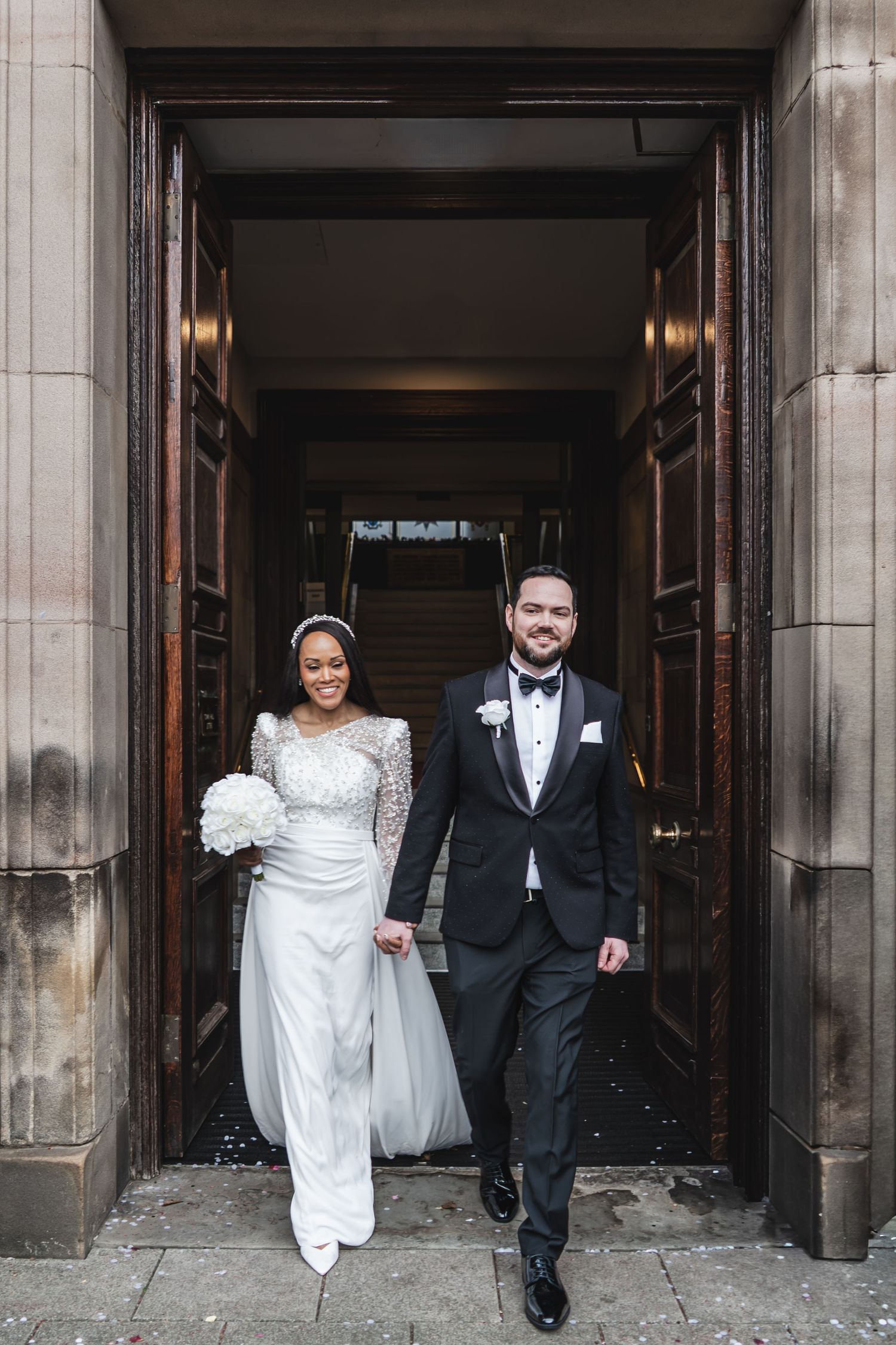 A wedding couple exits through stone archways in a sequence of four connected photos showing their joyful departure.