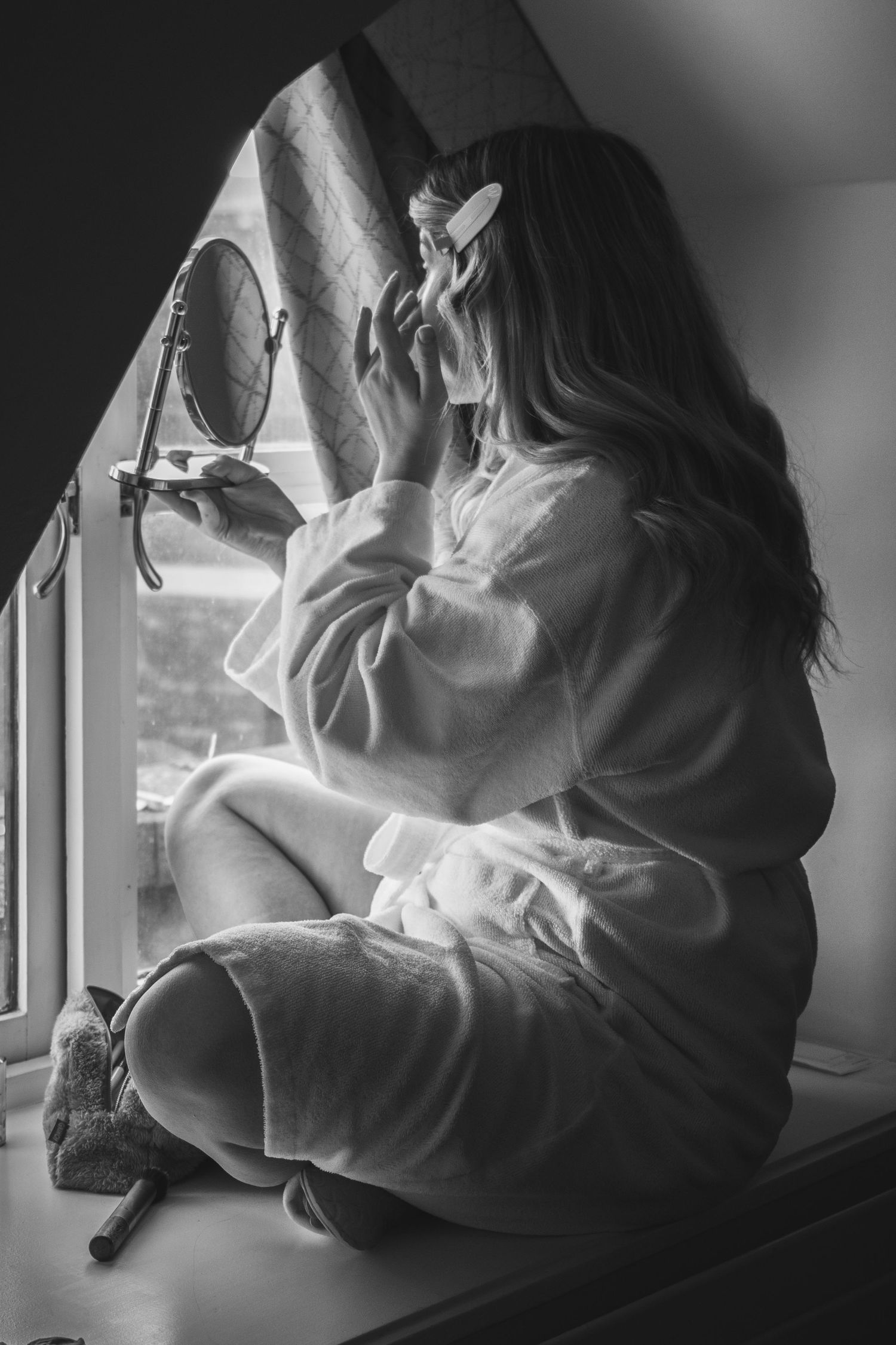 Silhouetted figure by window in moody black and white photograph.