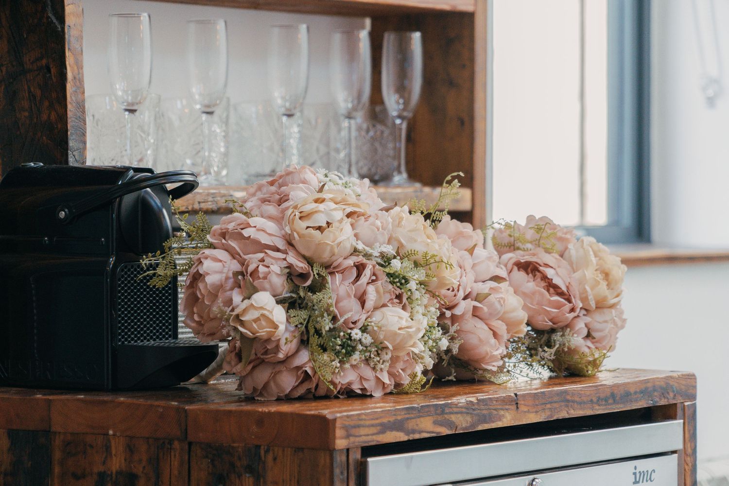 Wedding reception decor with delicate pink floral arrangements on wooden tables.