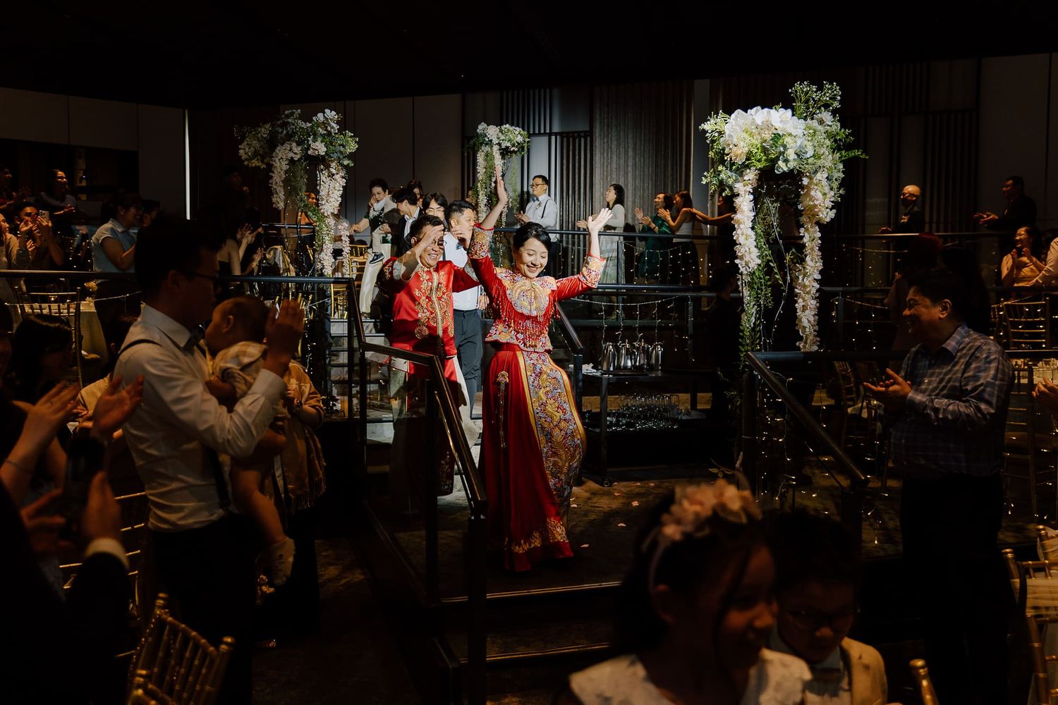 Wedding reception party at an elegantly decorated indoor venue with floral arches and ambient lighting.