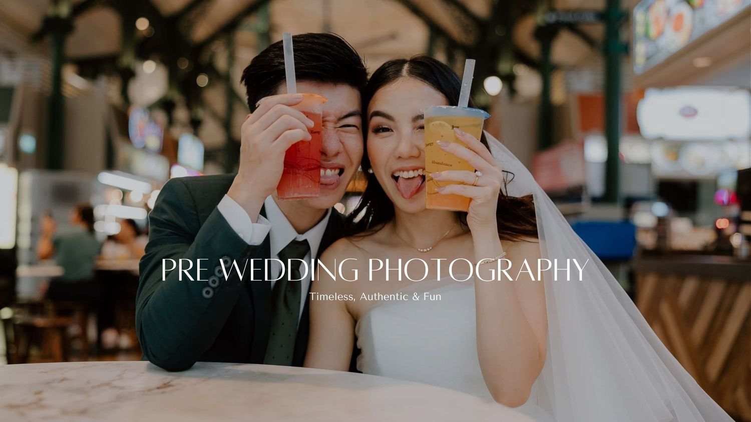 A joyful wedding couple shares a light-hearted moment holding coffee cups in front of their faces at a cafe.