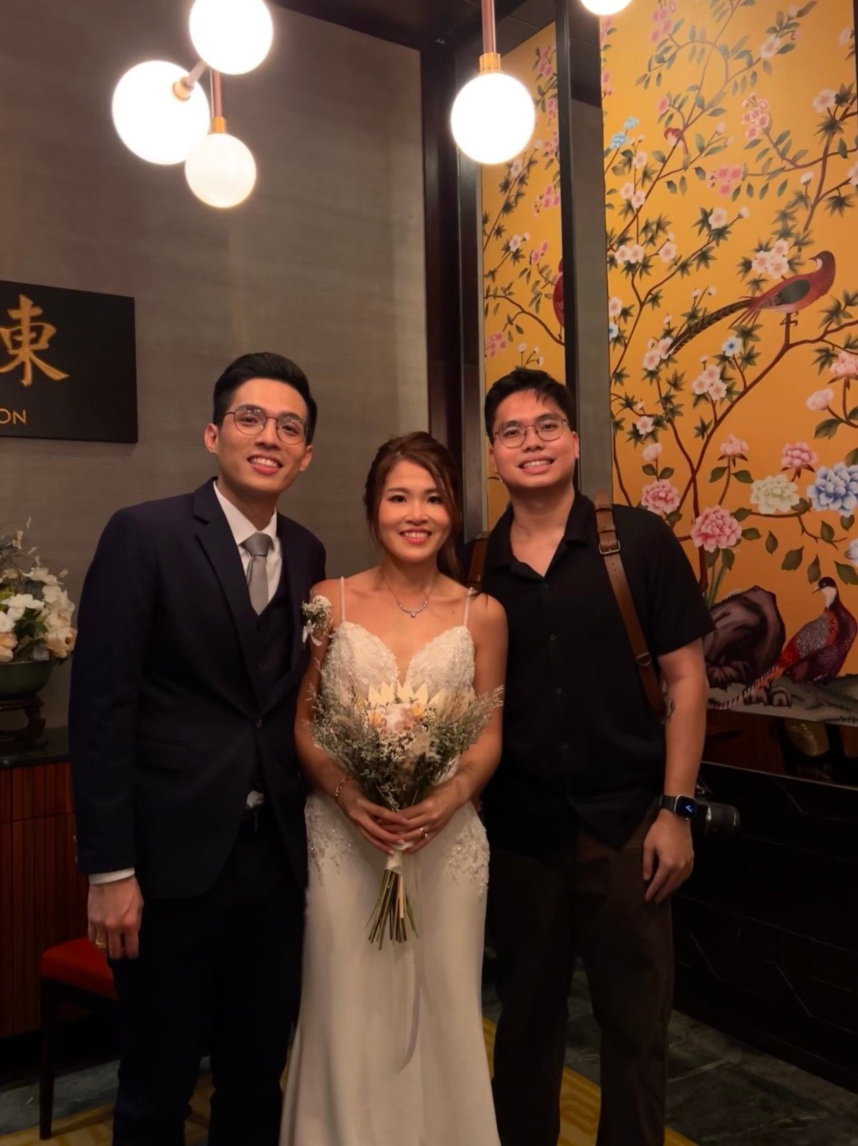 Wedding celebration at Asian restaurant with decorative yellow floral wallpaper and modern lighting.
