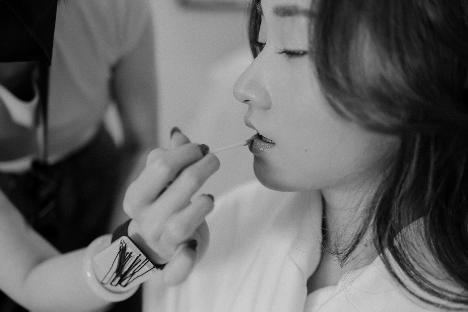 Black and white closeup shot of makeup being applied to person's lips.