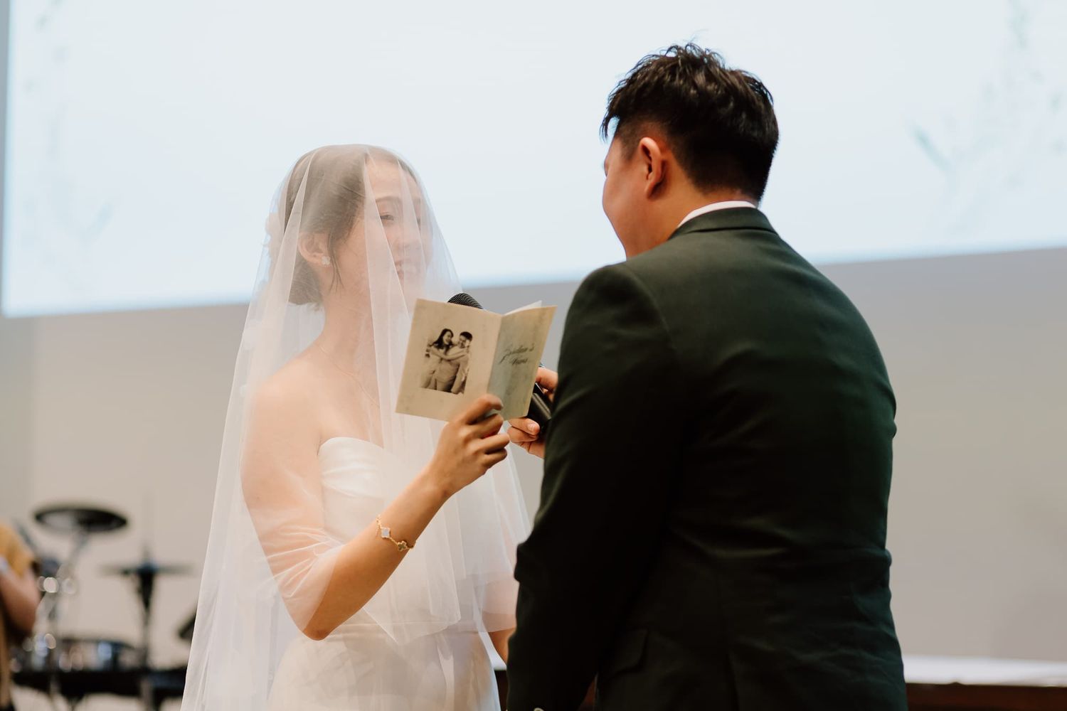 Intimate wedding ceremony moment captured at modern church altar with white flowers.