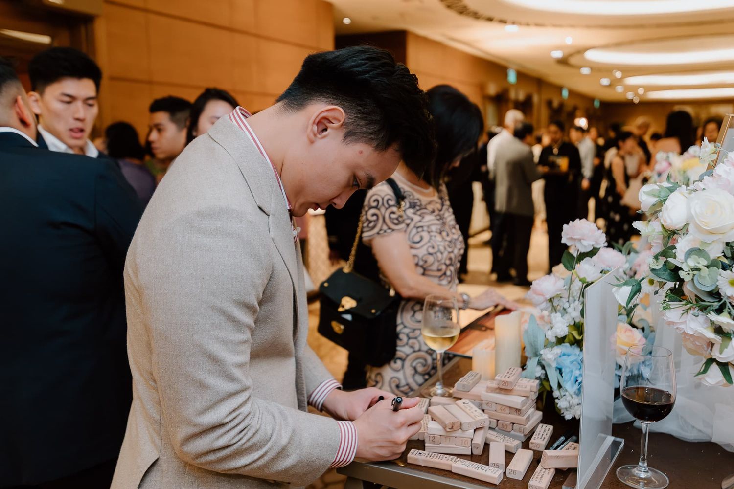 Guest signs guestbook at elegant wedding reception with floral decorations.
