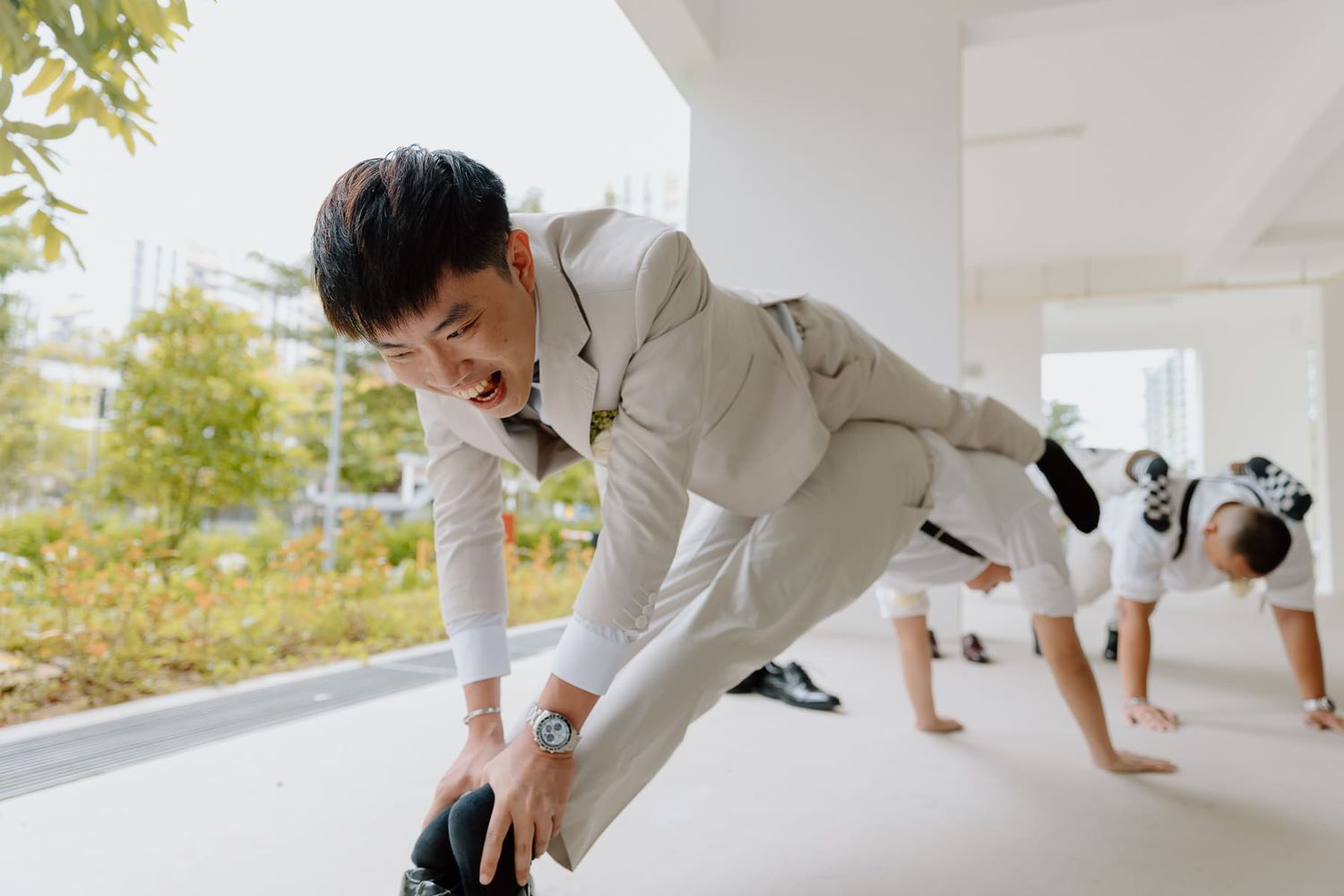 Groomsmen dressed in white suits engage in fun candid moments before the ceremony.