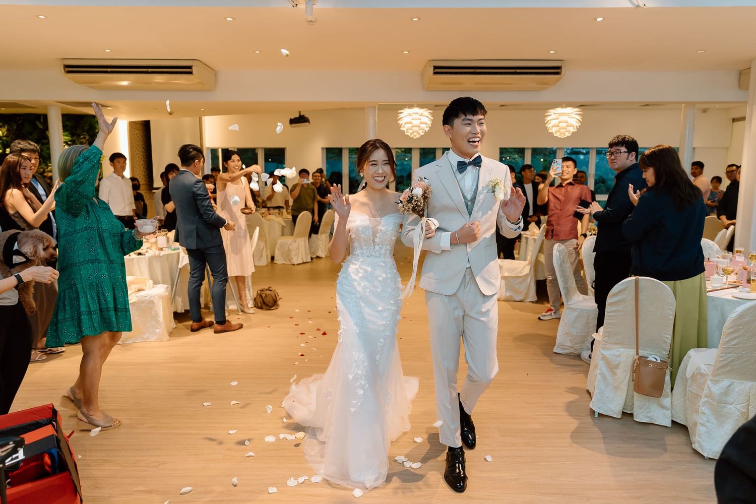 An elegant white indoor wedding venue with scattered flower petals on the floor.