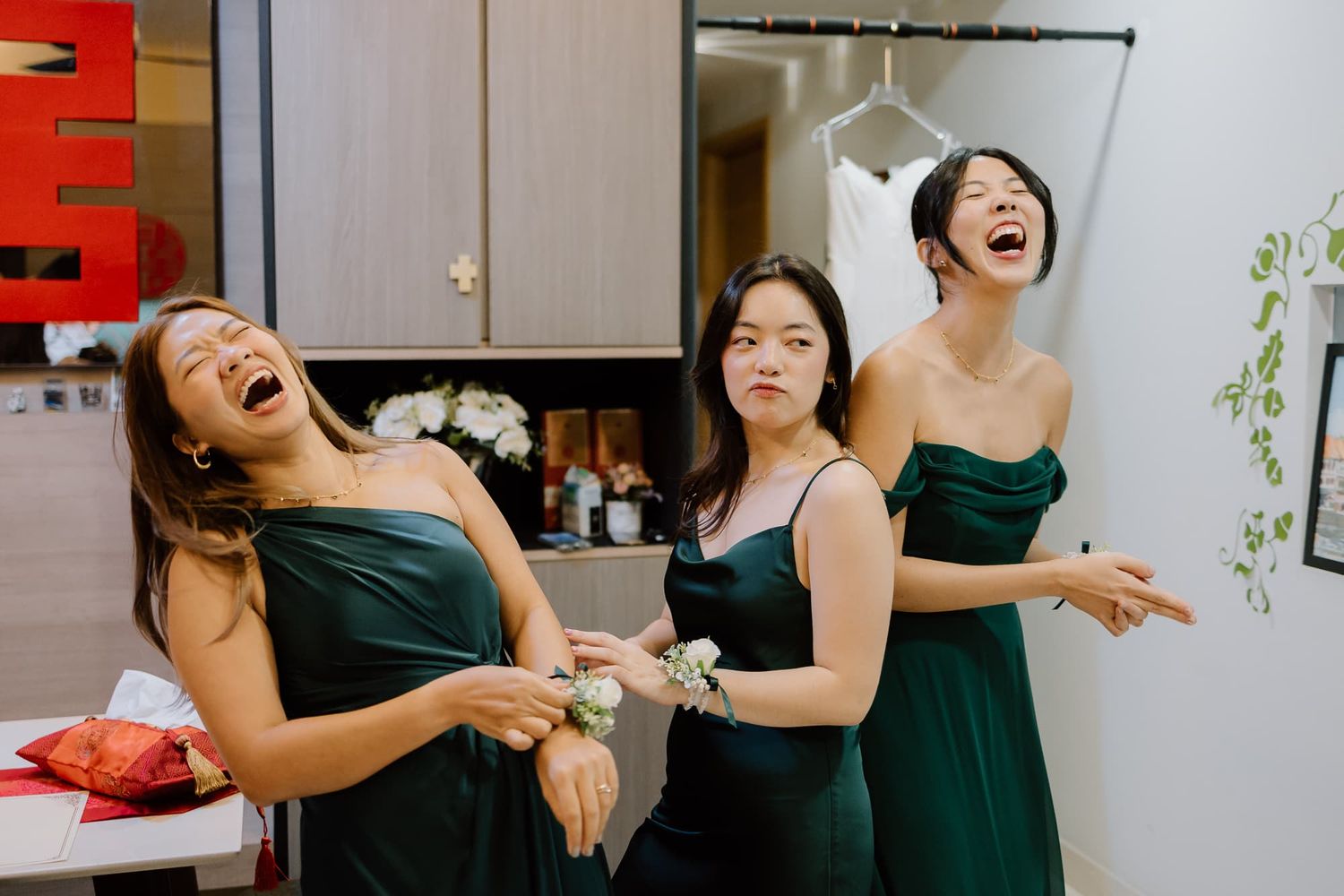 Candid moment of joy shared between bridesmaids in elegant dark green dresses.