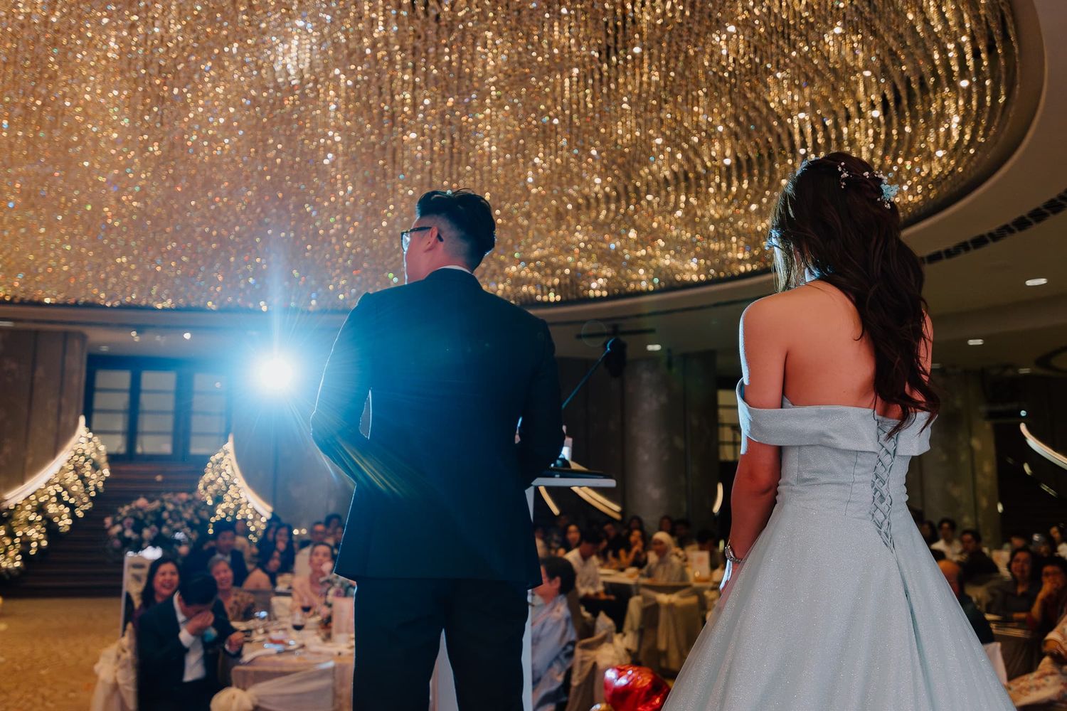 Wedding celebration under sparkling crystal chandeliers in an elegant ballroom.