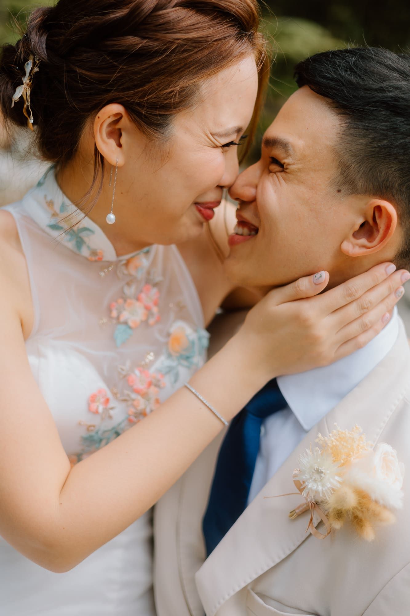 A romantic wedding couple share an intimate moment while wearing traditional Chinese qipao dress and white suit.