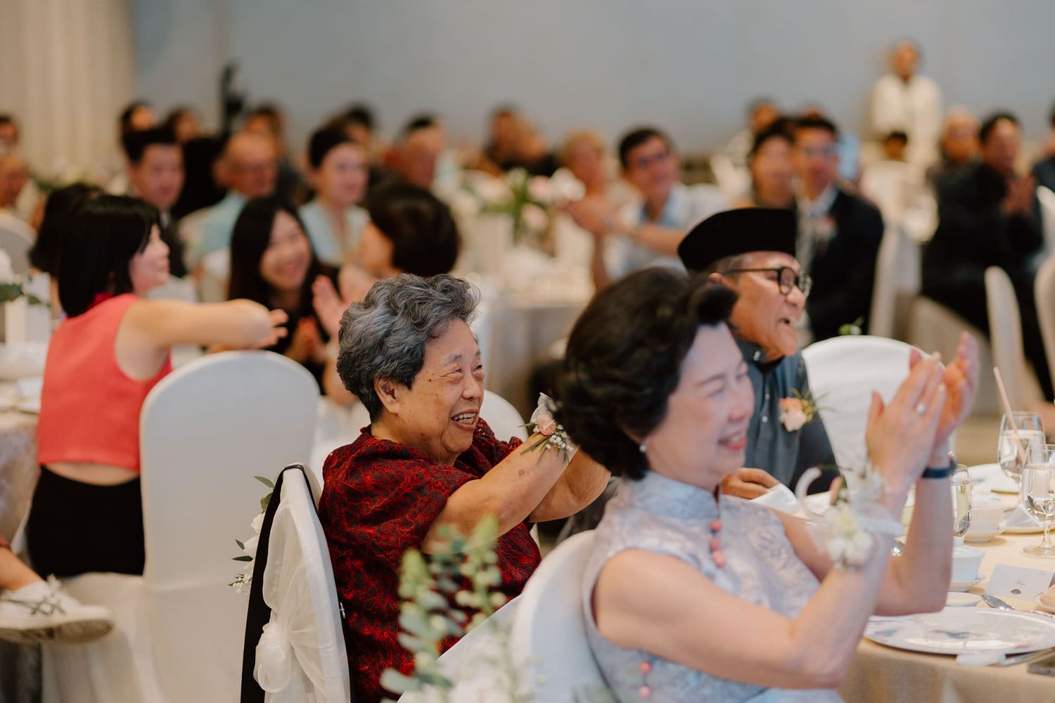 A group of people celebrating at a wedding reception with tables, decorations, and lively dancing.