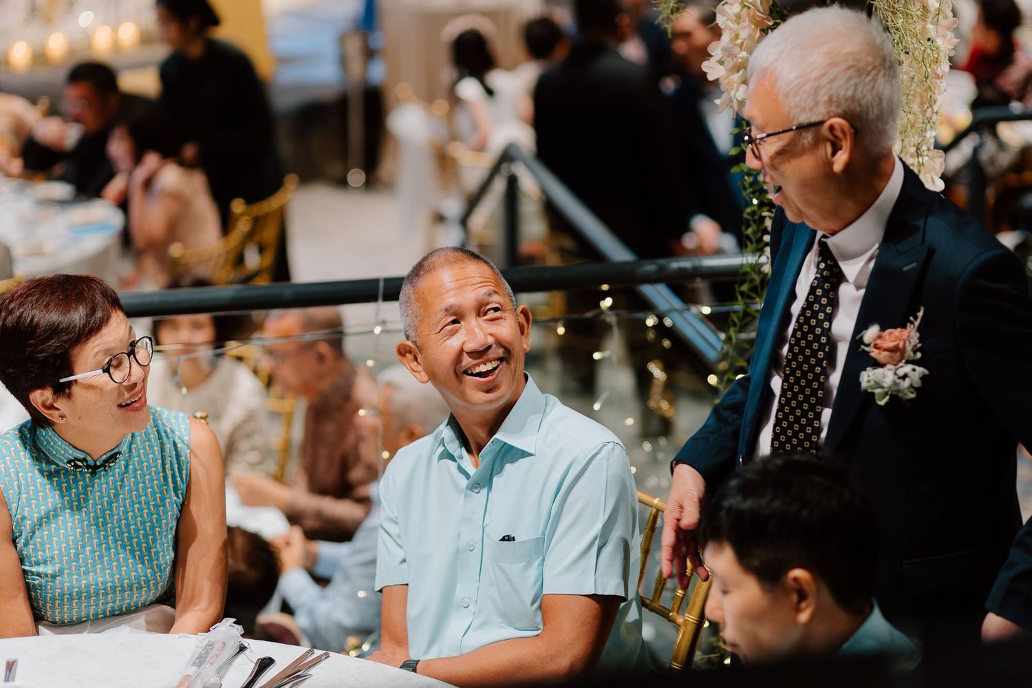 Wedding guests laugh and smile during an intimate indoor reception gathering.