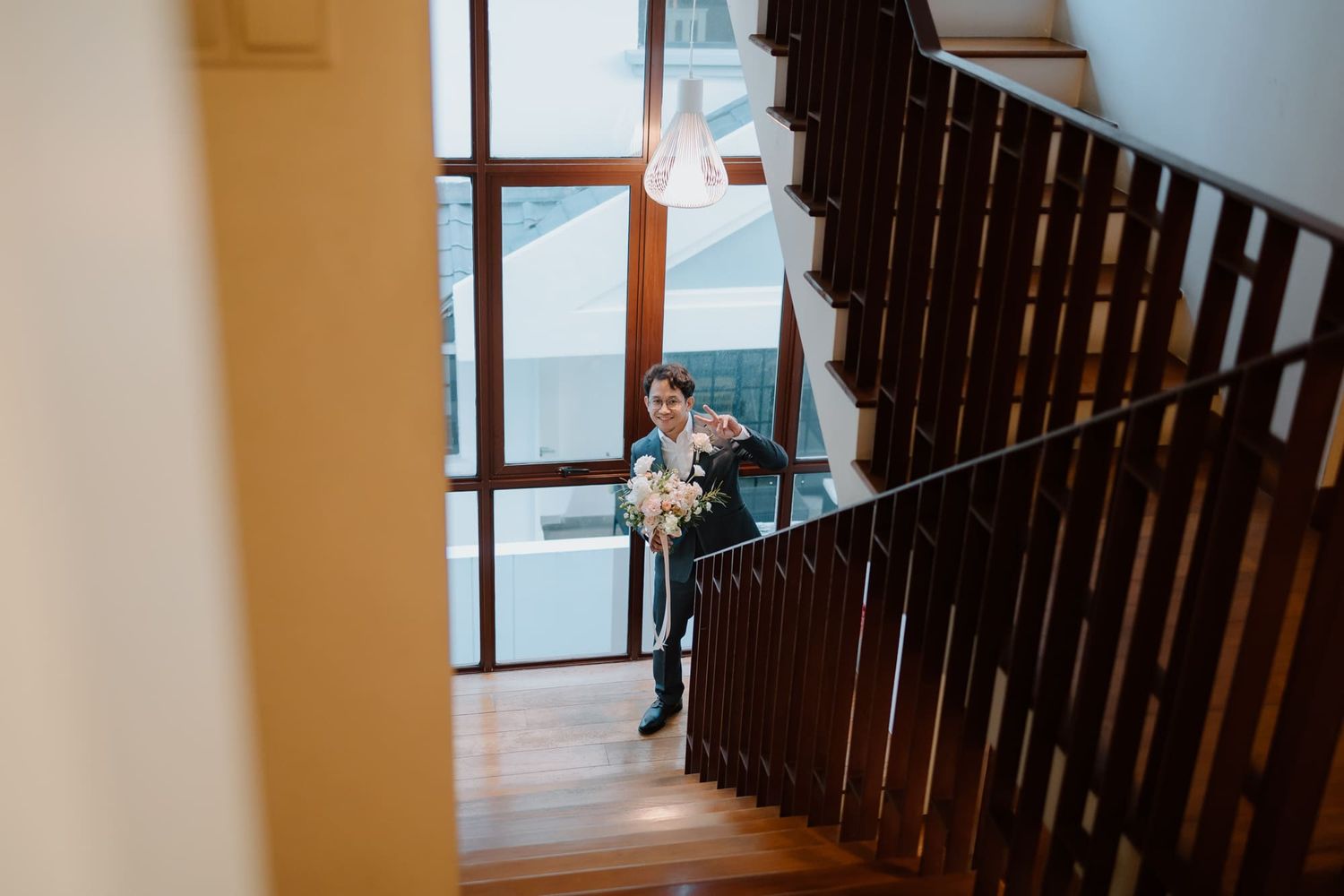 Dark wooden staircase railing against a white wall in an interior hallway.