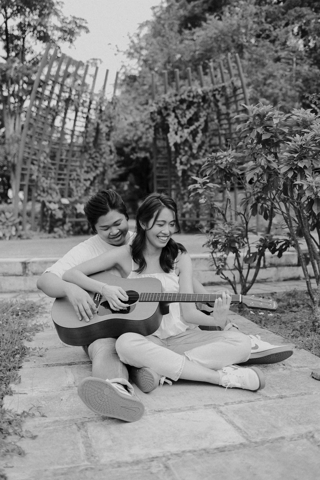 Black and white photo of couple sharing guitar music on stone steps.