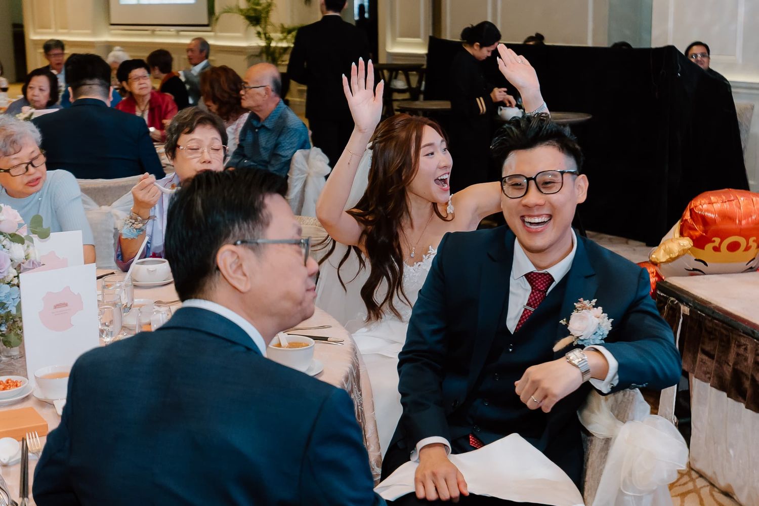 Joyful celebration moment captured during wedding reception with guests at banquet tables.