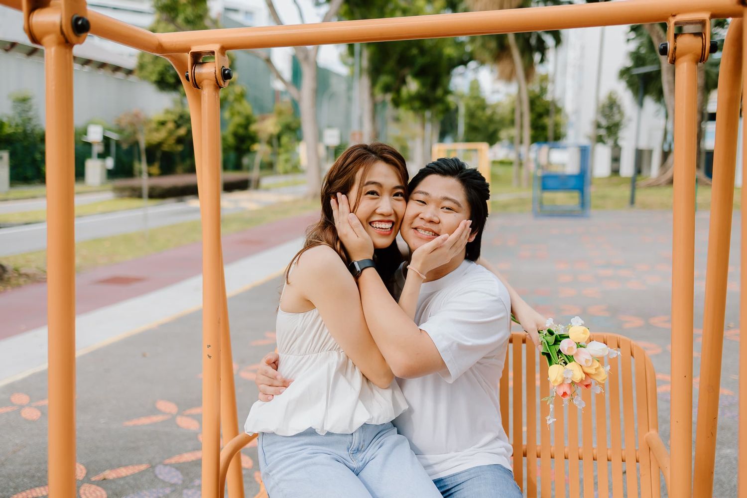 Playful interaction under orange metal structure in outdoor setting.