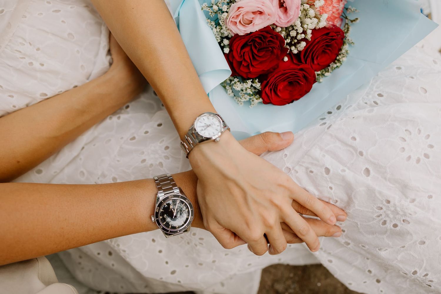 Close-up of hands with wedding bouquet featuring red and pink flowers.