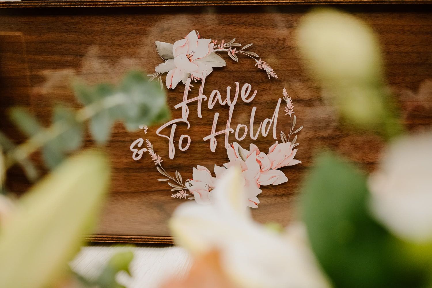 Rustic wooden wedding sign with delicate floral decorations.