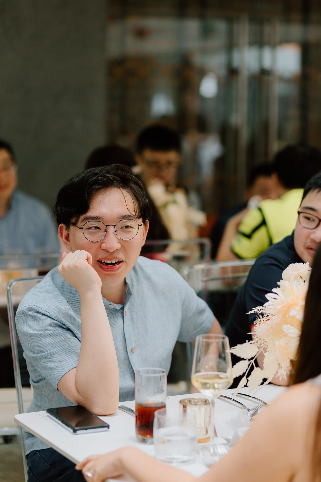 Wedding reception guests enjoying conversation at dining tables with glassware.