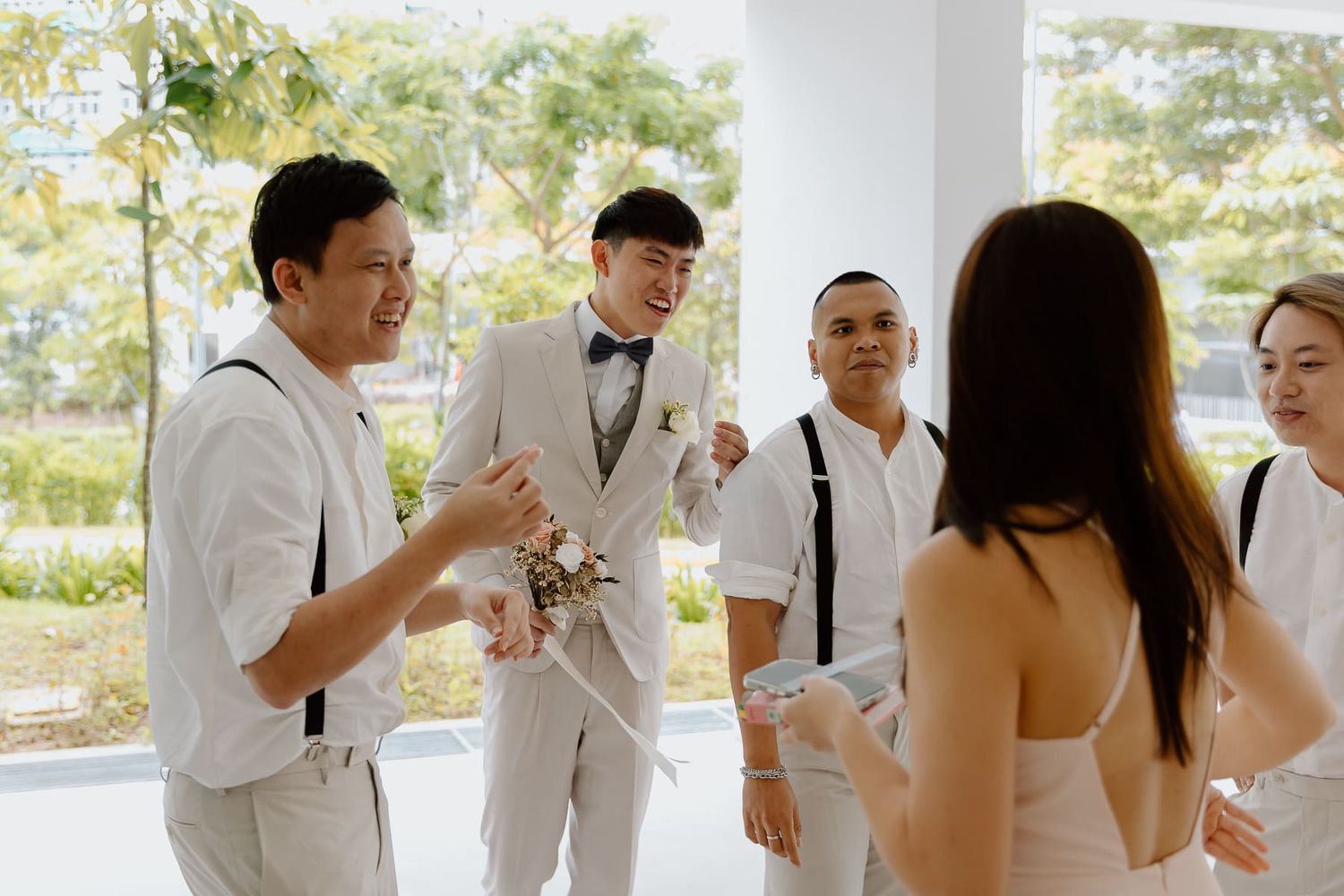 Wedding party members in white attire sharing celebratory drinks together.