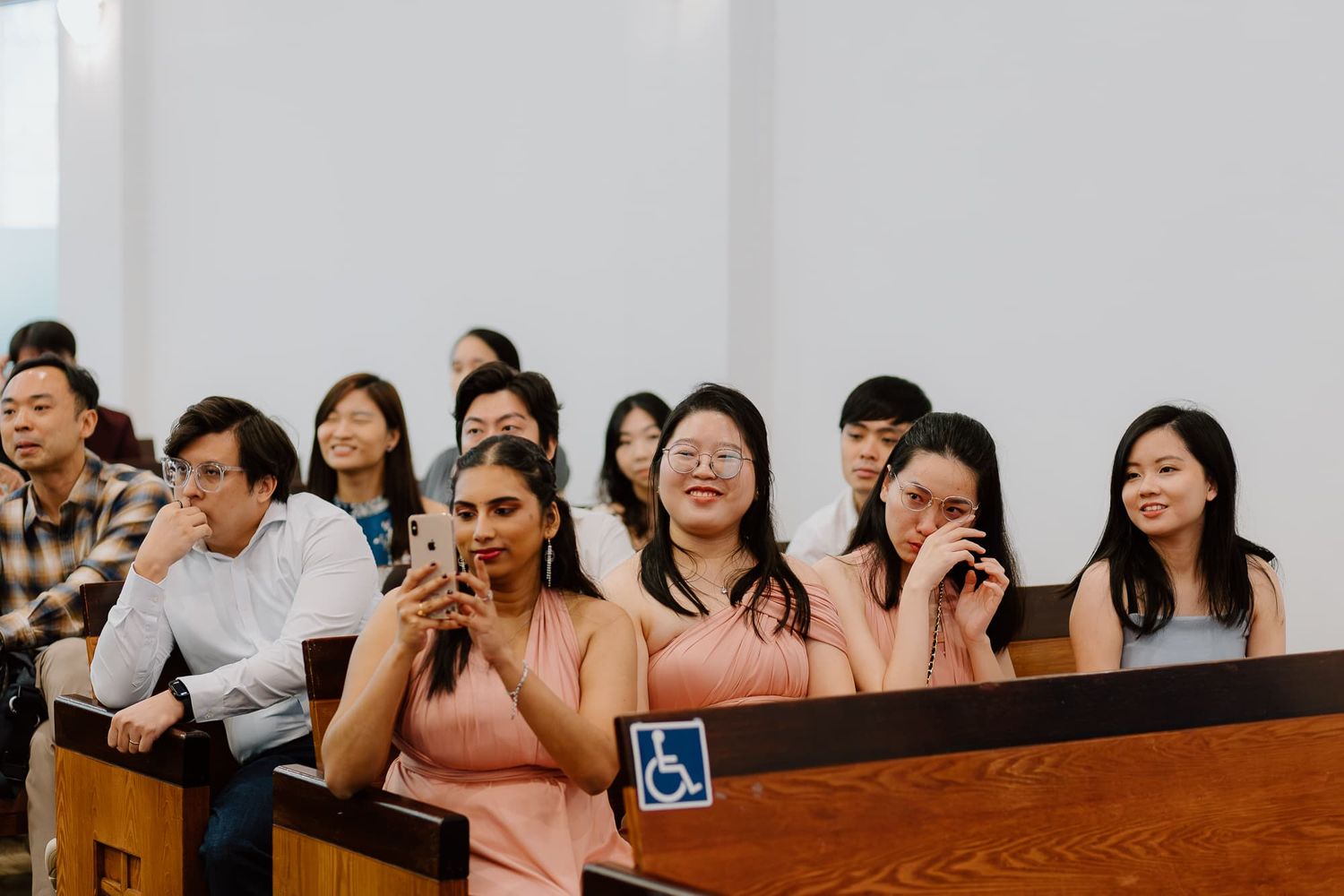 Wedding guests react emotionally during ceremony in church pews.