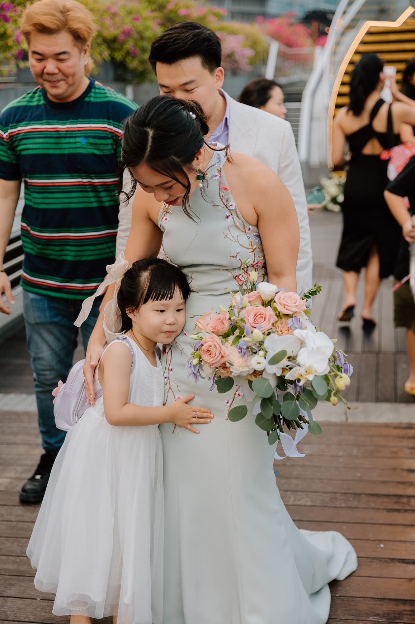 A touching moment at an outdoor celebration with a flower bouquet and cityscape views.