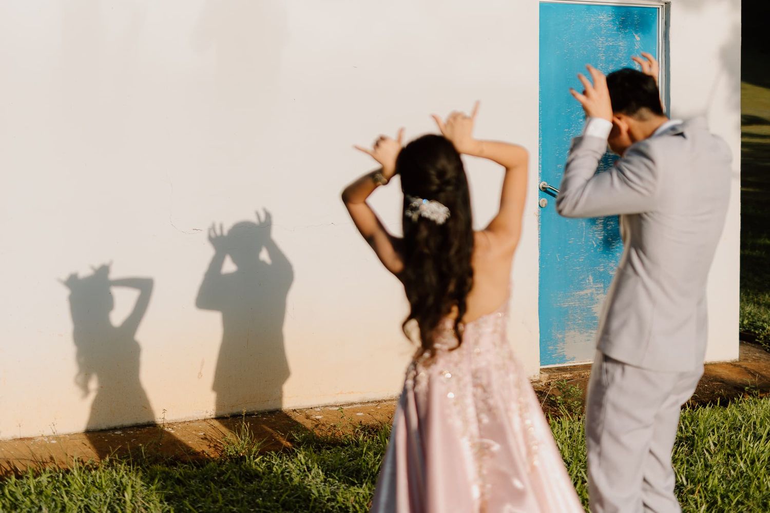 Couple casting fun shadows on a white wall while dancing and posing outdoors.