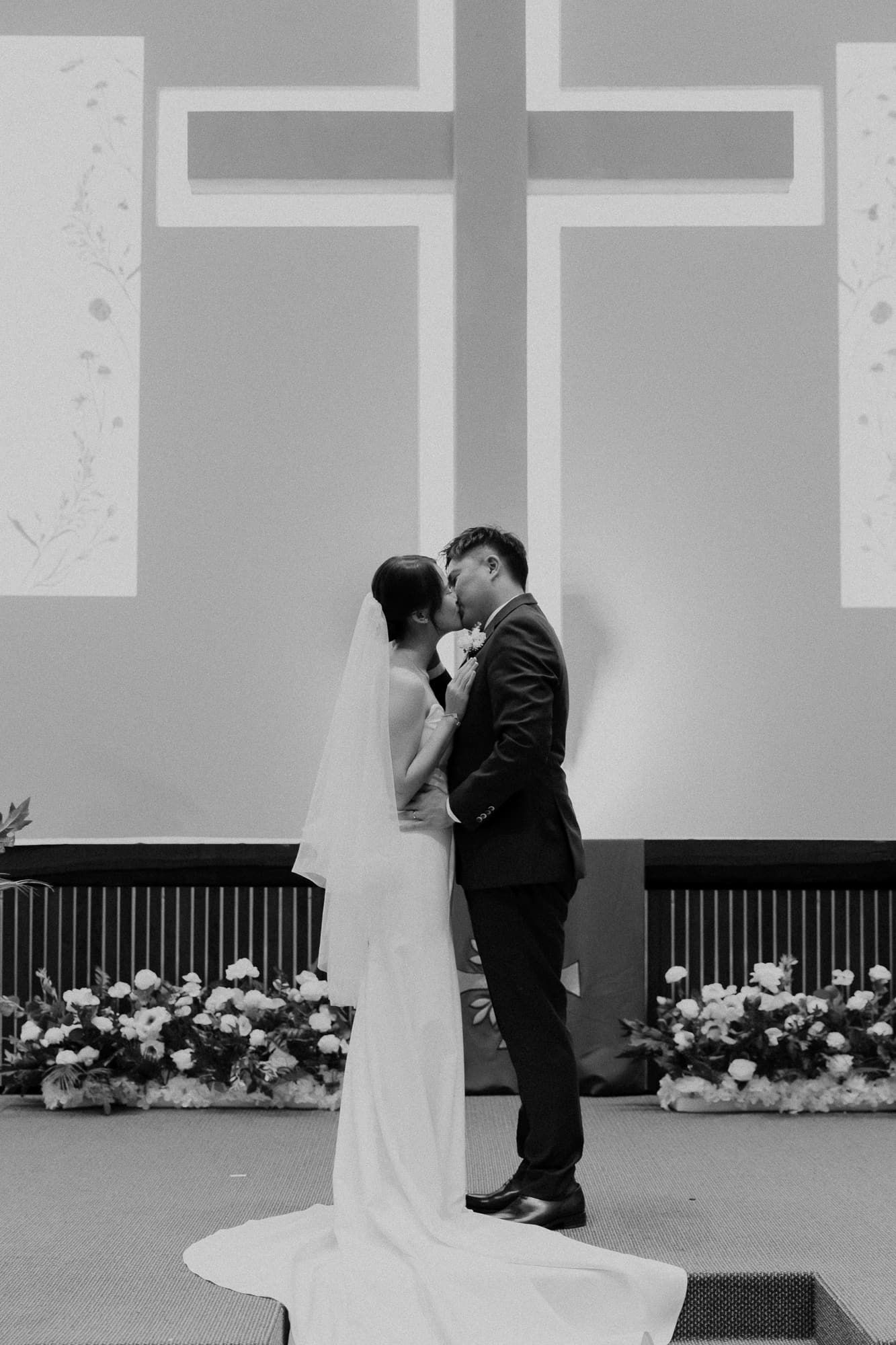 Black and white photo captures intimate wedding ceremony moments at church altar.