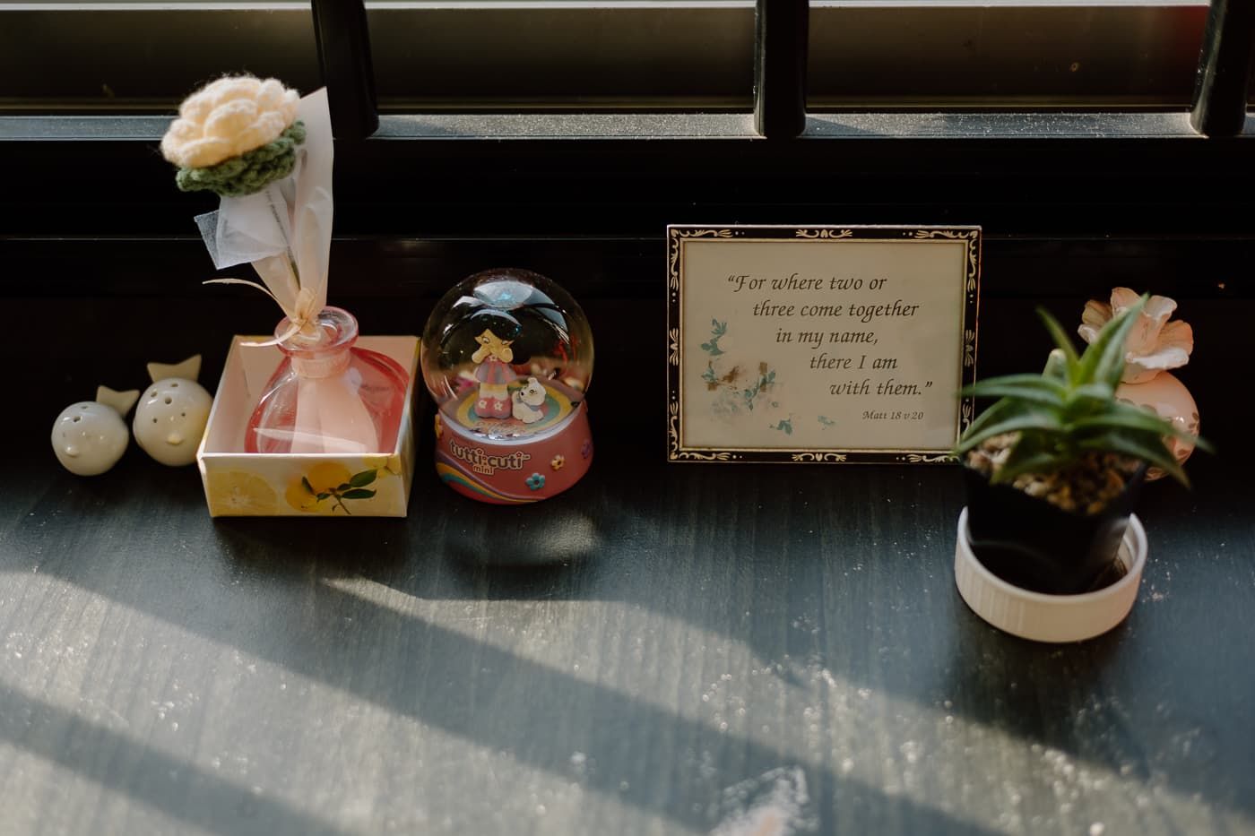 Small decorative vases and flowers arranged on a window ledge with a framed note.