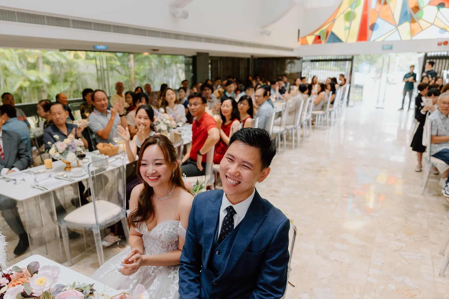 Bright wedding reception space filled with guests and festive decorations.